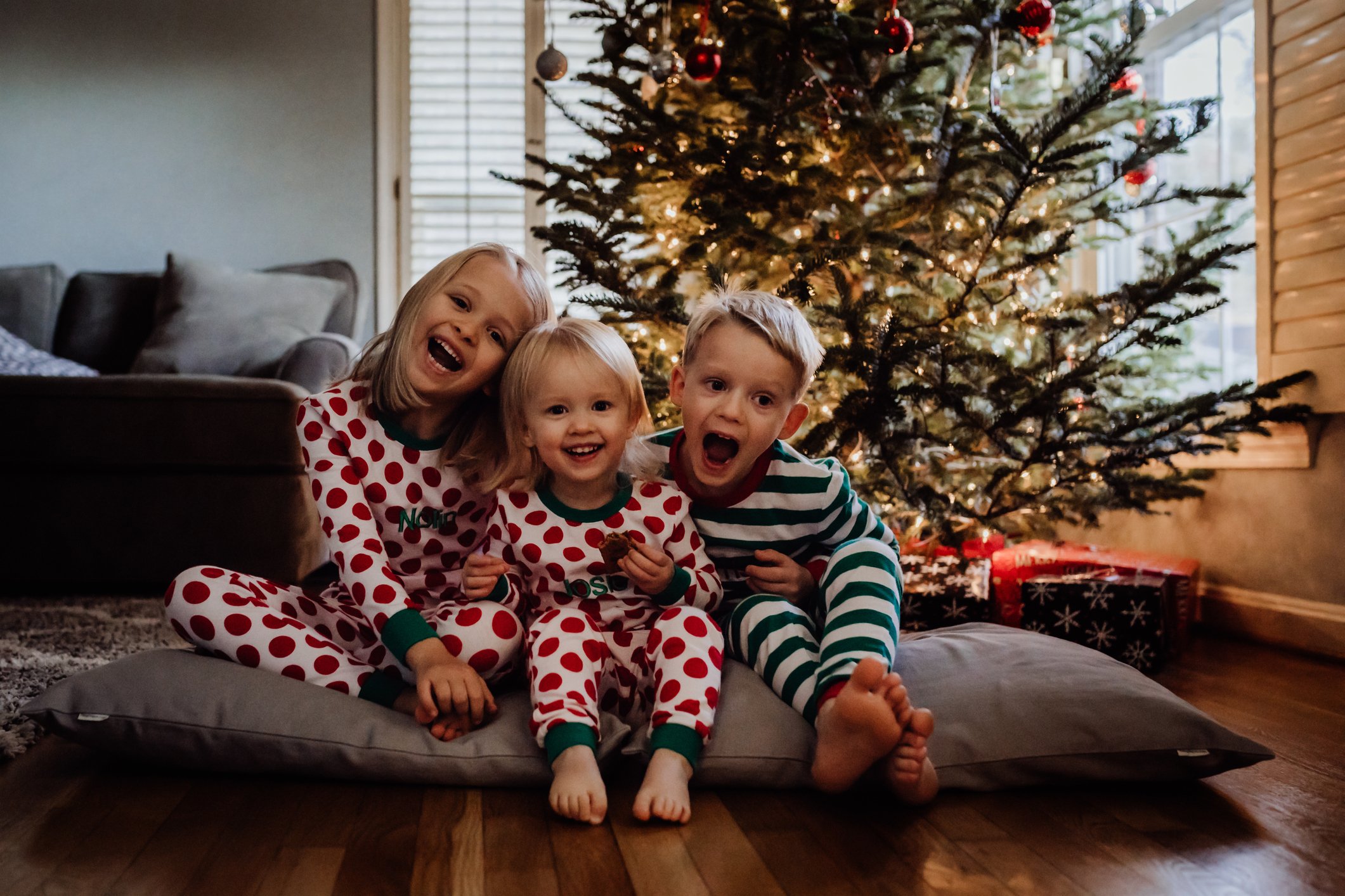 Geschwister sitzen zu Hause bei einem Weihnachtsbaum I Quelle: Getty Images