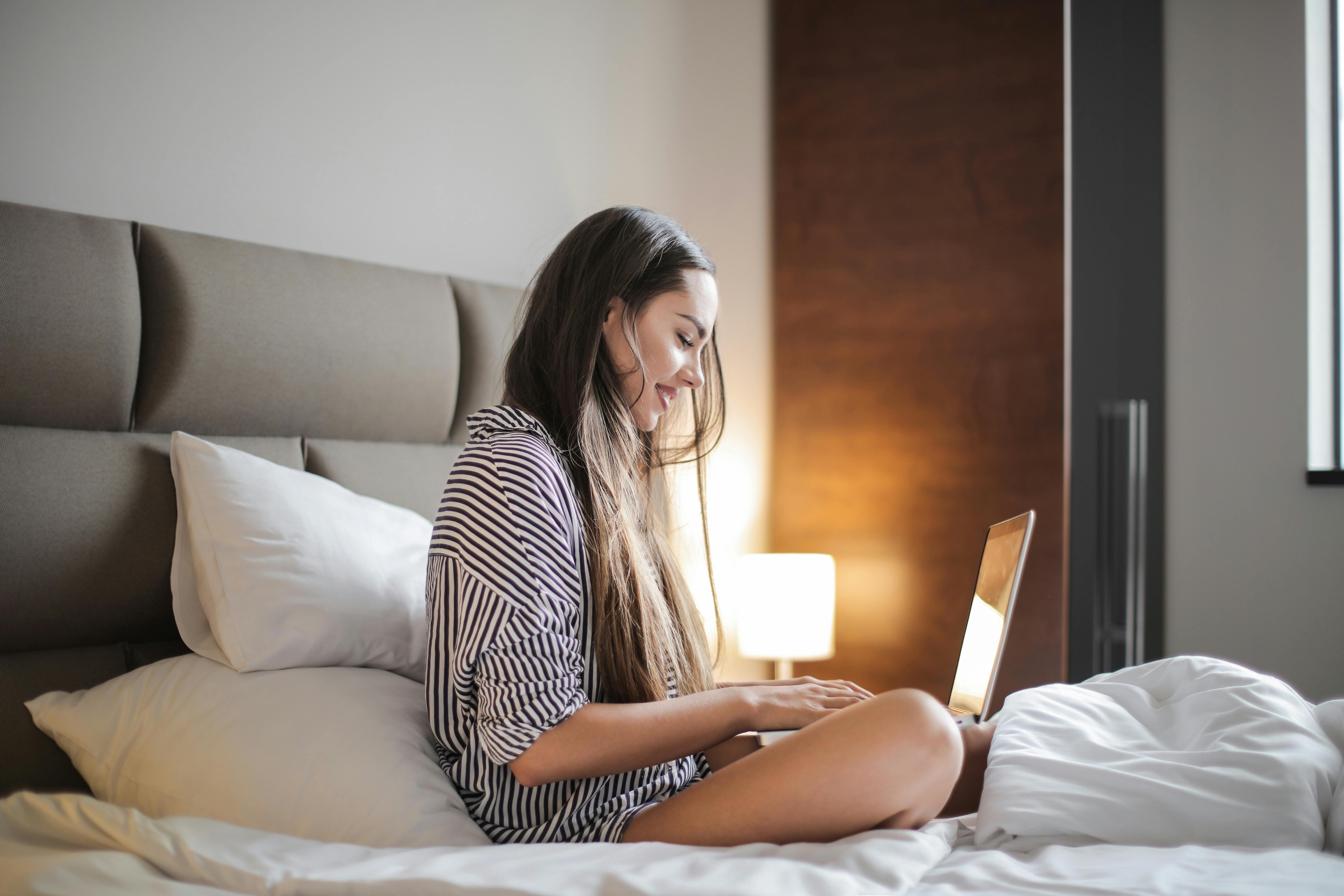 A woman sitting in bed and using her laptop | Source: Pexels