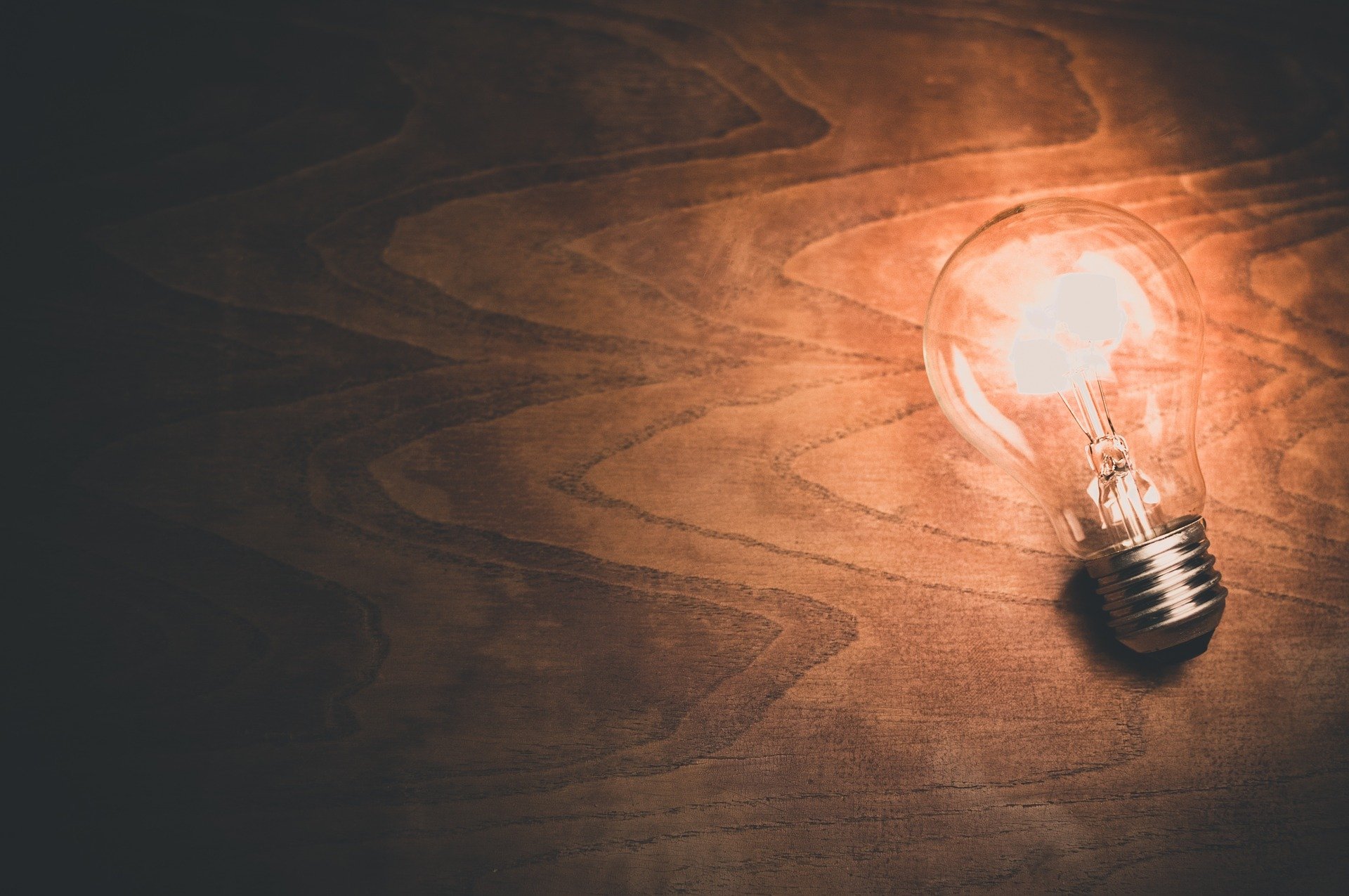 A light bulb on a table. | Photo: Pixabay/Free-Photos 