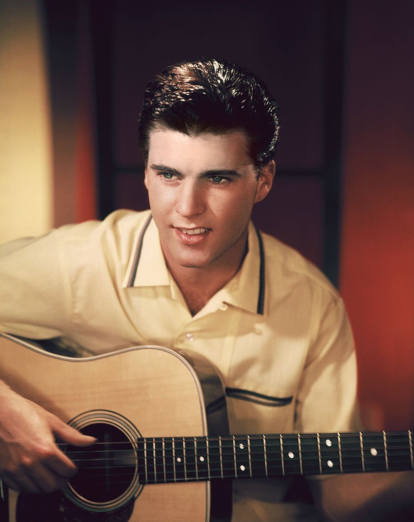 Ricky Nelson playing  a guitar as he  posed for a snapshot. | Source: Getty Images