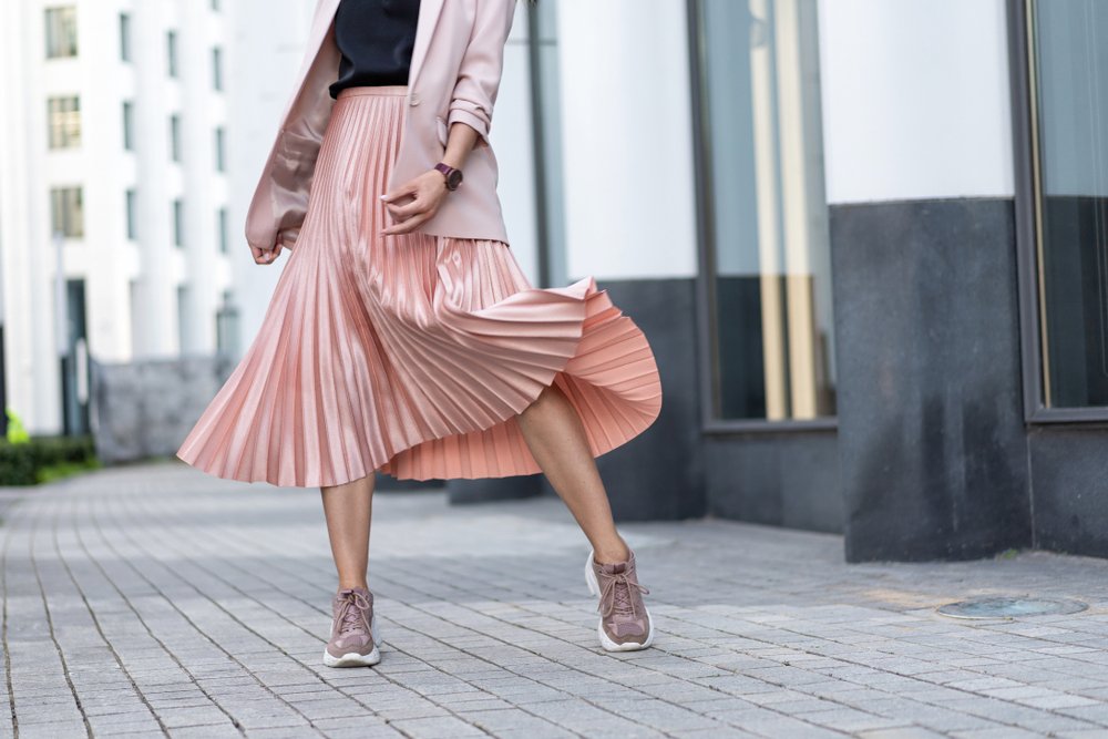 Mujer usando una falta plisada de color rosa por debajo de la rodilla con zapatos deportivos. | Foto: Shutterstock Mujer usando una falta plisada de color rosa por debajo de la rodilla con zapatos deportivos. | Foto: Shutterstock