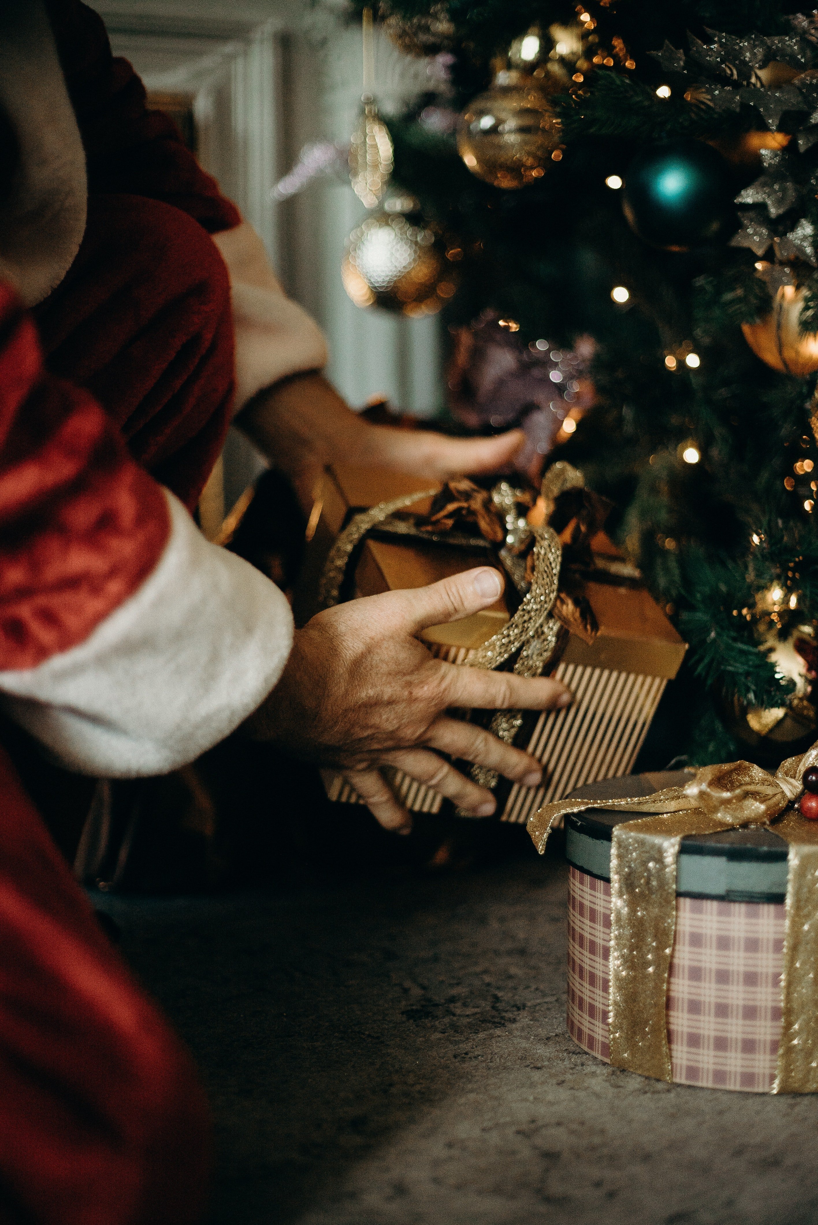 Santa secretly putting a gift under the Christmas tree. | Source: Pexels.