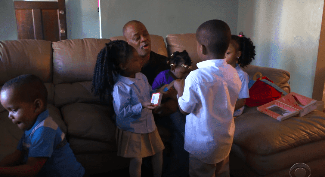 Lamont Thomas and his children on the sofa in the living room of their home. | Photo: YouTube/CBS Evening News
