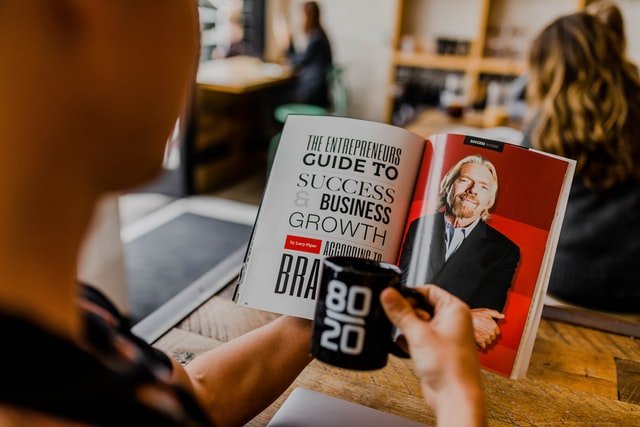 Man reading magazine with Richard Branson's face | Source: Unsplash