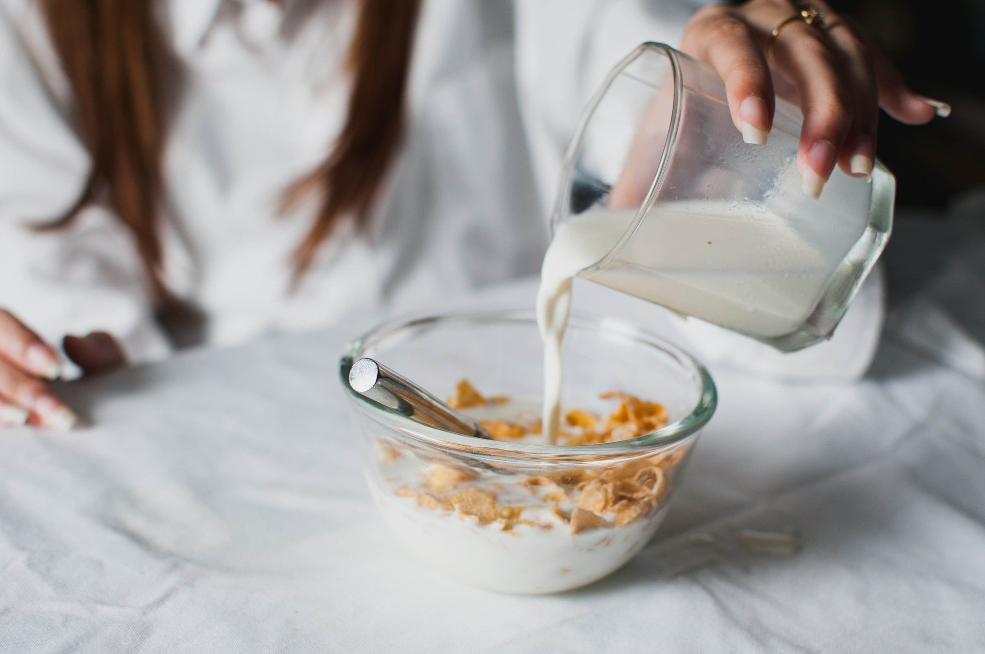 A woman pouring some milk into a cereal bowl | Photo: Pixabay/fancycrave1