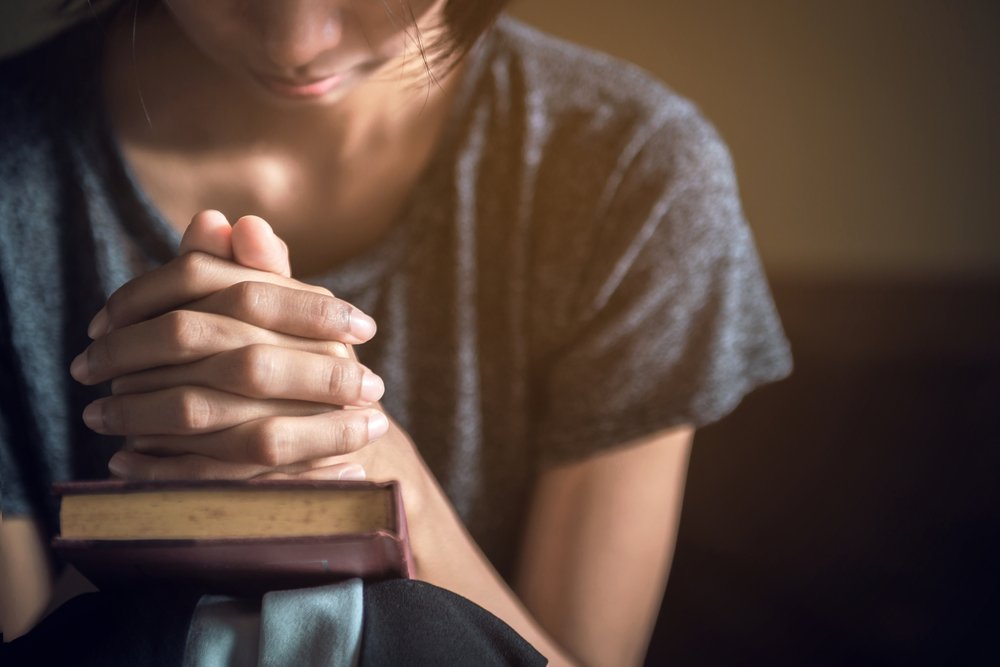Mujer orando sobre una Biblia. | Foto: Shutterstock