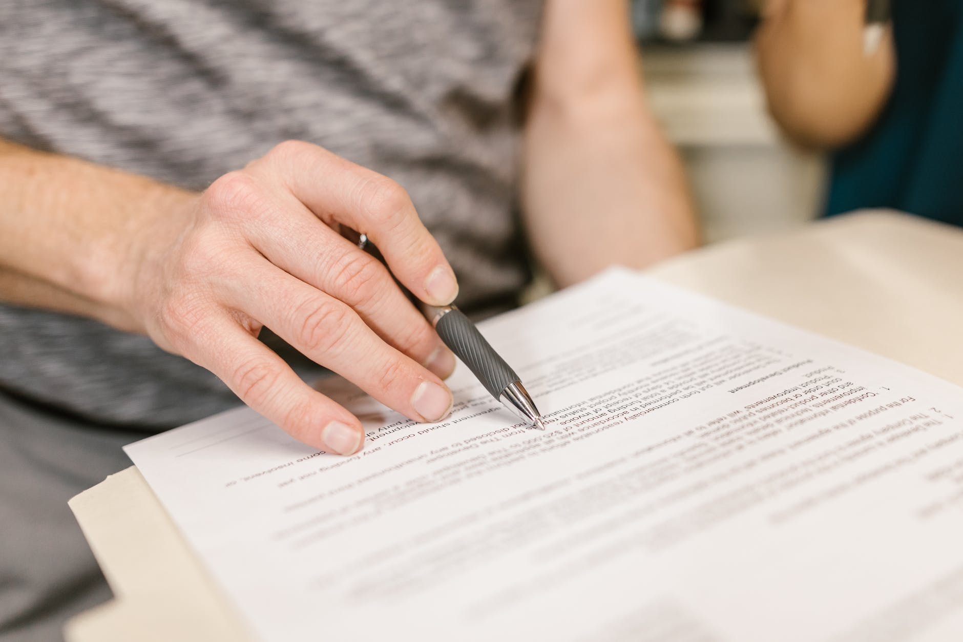 Persona con un bolígrafo sobre un documento. | Foto: Pexels 