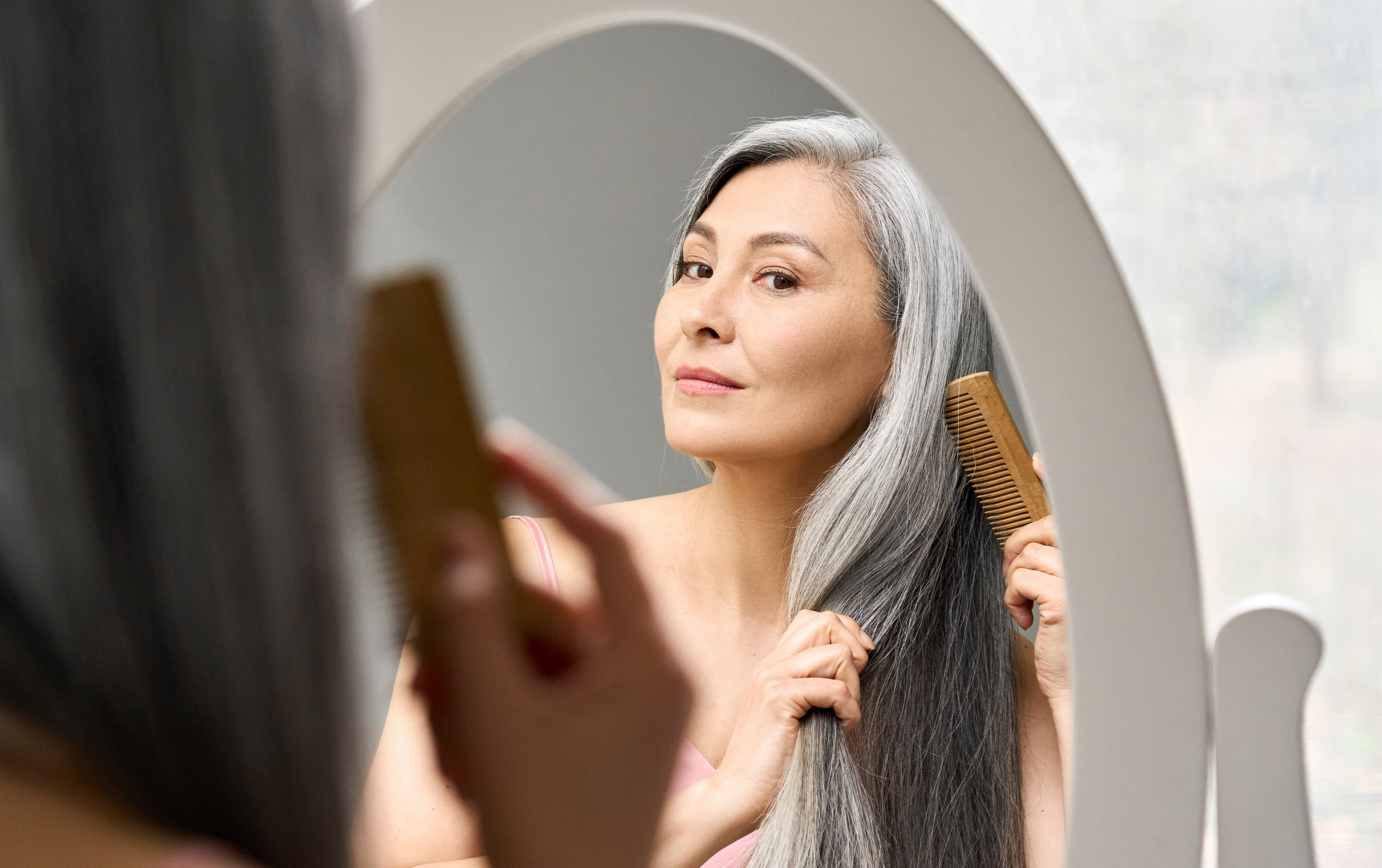 Gray-haired woman combing her hair. | Source: Shutterstock