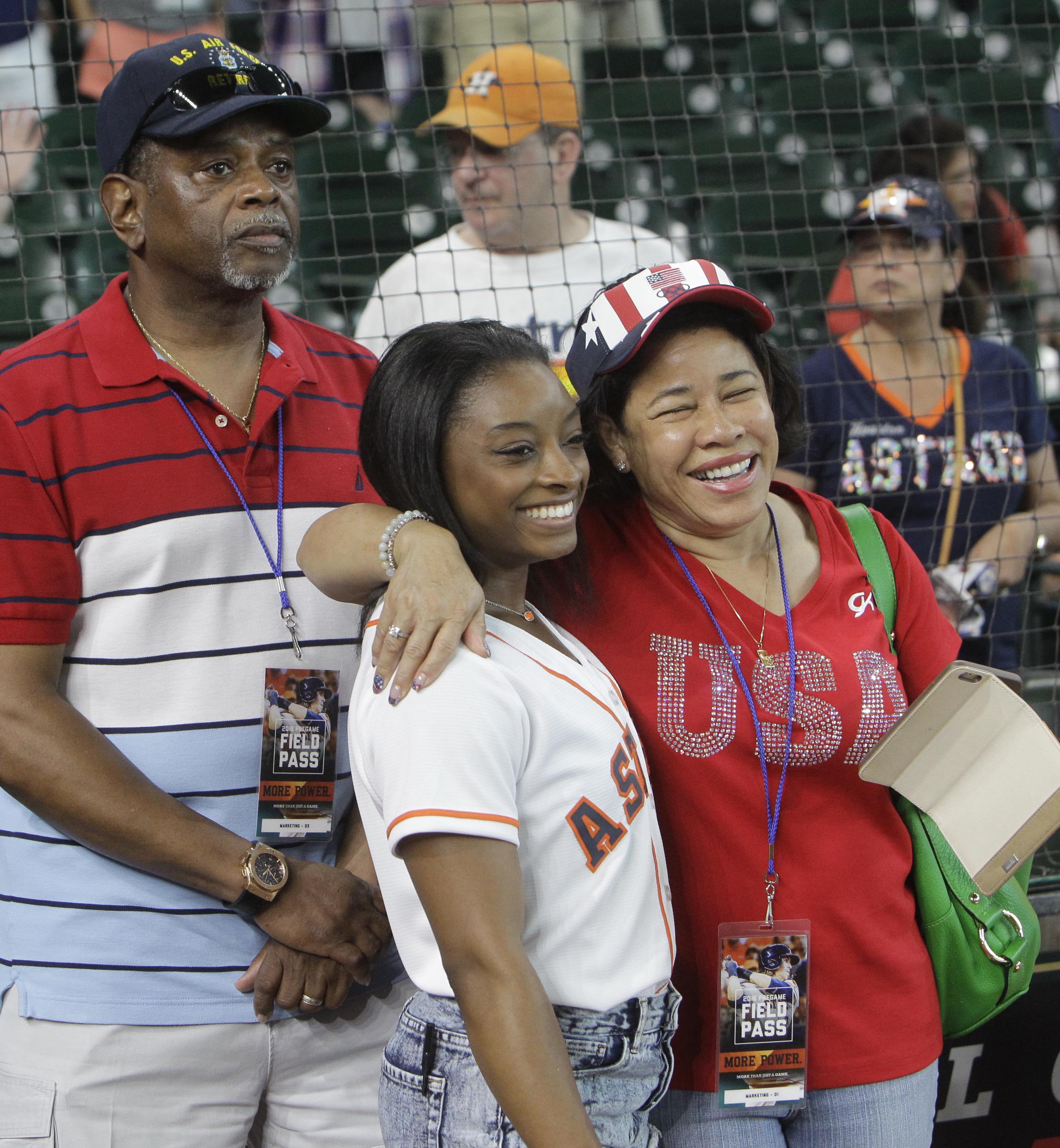 Simone Biles, with her parents, Ron and Nellie Biles, as they wait for her ceremonial first pitch at a game on July 4, 2016, in Houston | Source: Getty Images