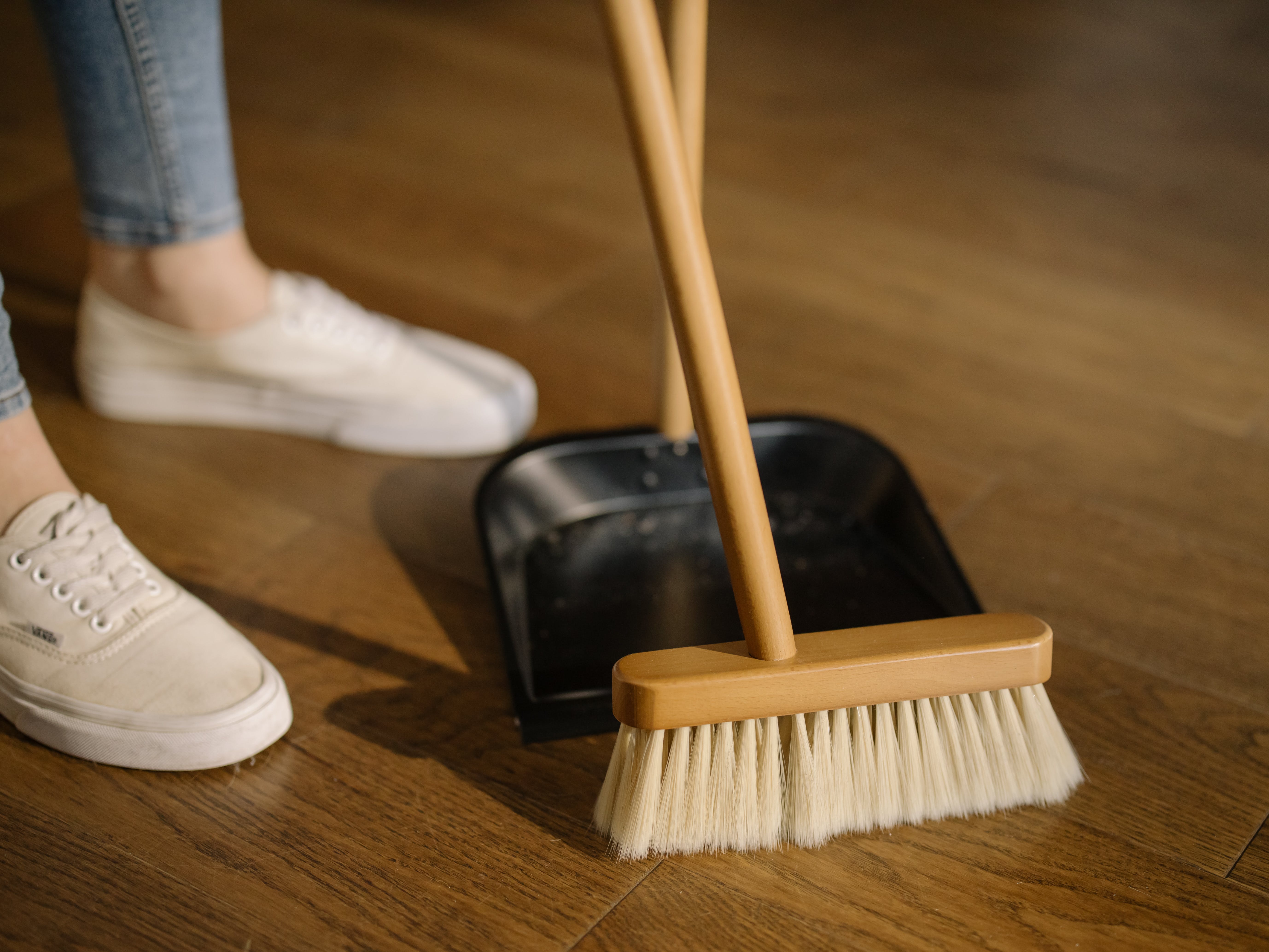 Someone sweeping up dirt with a broom and dustpan | Source: Pexels