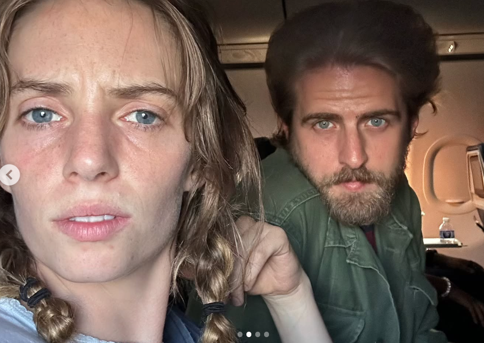 A candid airplane selfie captures Maya Hawke with braided hair staring seriously into the camera while Christian Hutson leans in from behind her seat. | Source: Instagram/maya_hawke