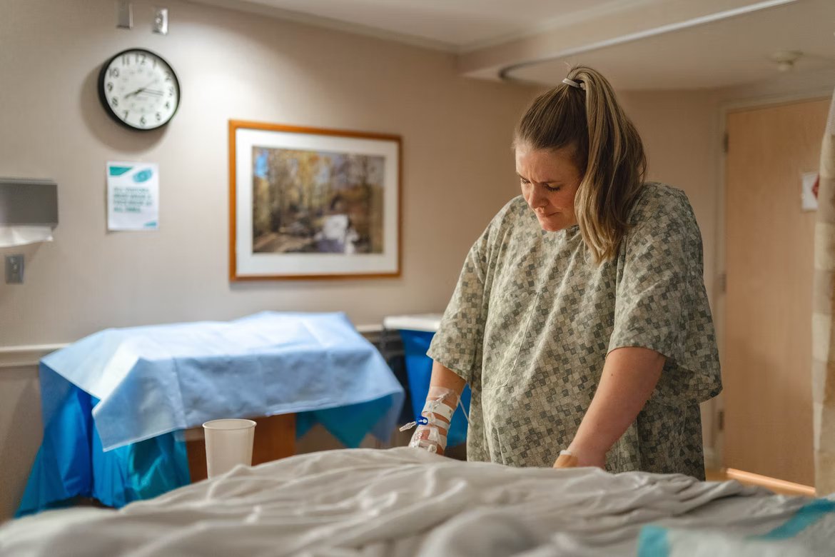 Una mujer embarazada con gesto de dolor en una habitación de hospital. | Foto: Unsplash