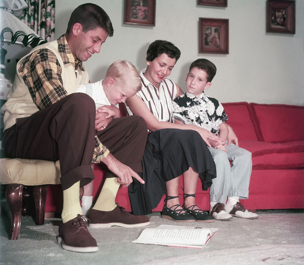 Der amerikanische Schauspieler und Komiker Jerry Lewis sitzt mit seiner Frau Patti Palmer und ihren beiden Söhnen Gary und Ronald um 1960 auf einer Couch | Quelle: Getty Images