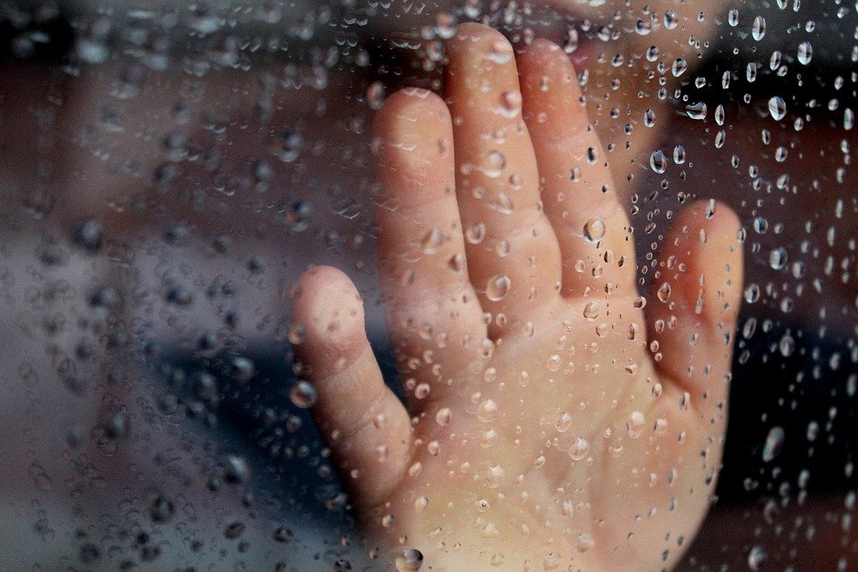 La mano de un hombre sobre el vidrio de una ventana lleno de gotas de agua. | Foto: Pixabay