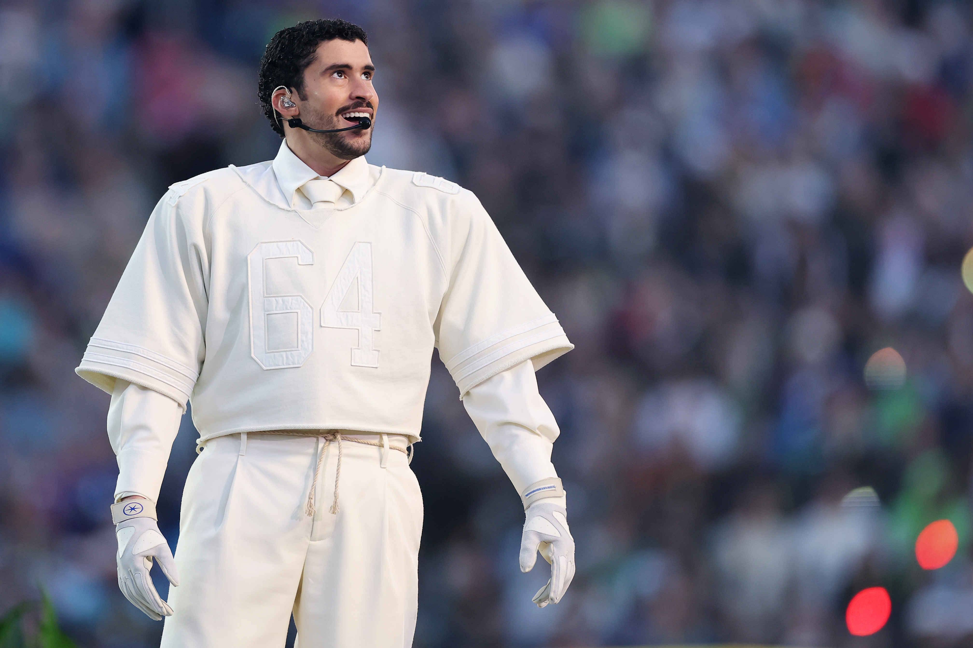 Bad Bunny performs during the Super Bowl 2026 halftime show, wearing an all-white outfit as he takes the stage in front of a packed stadium audience.