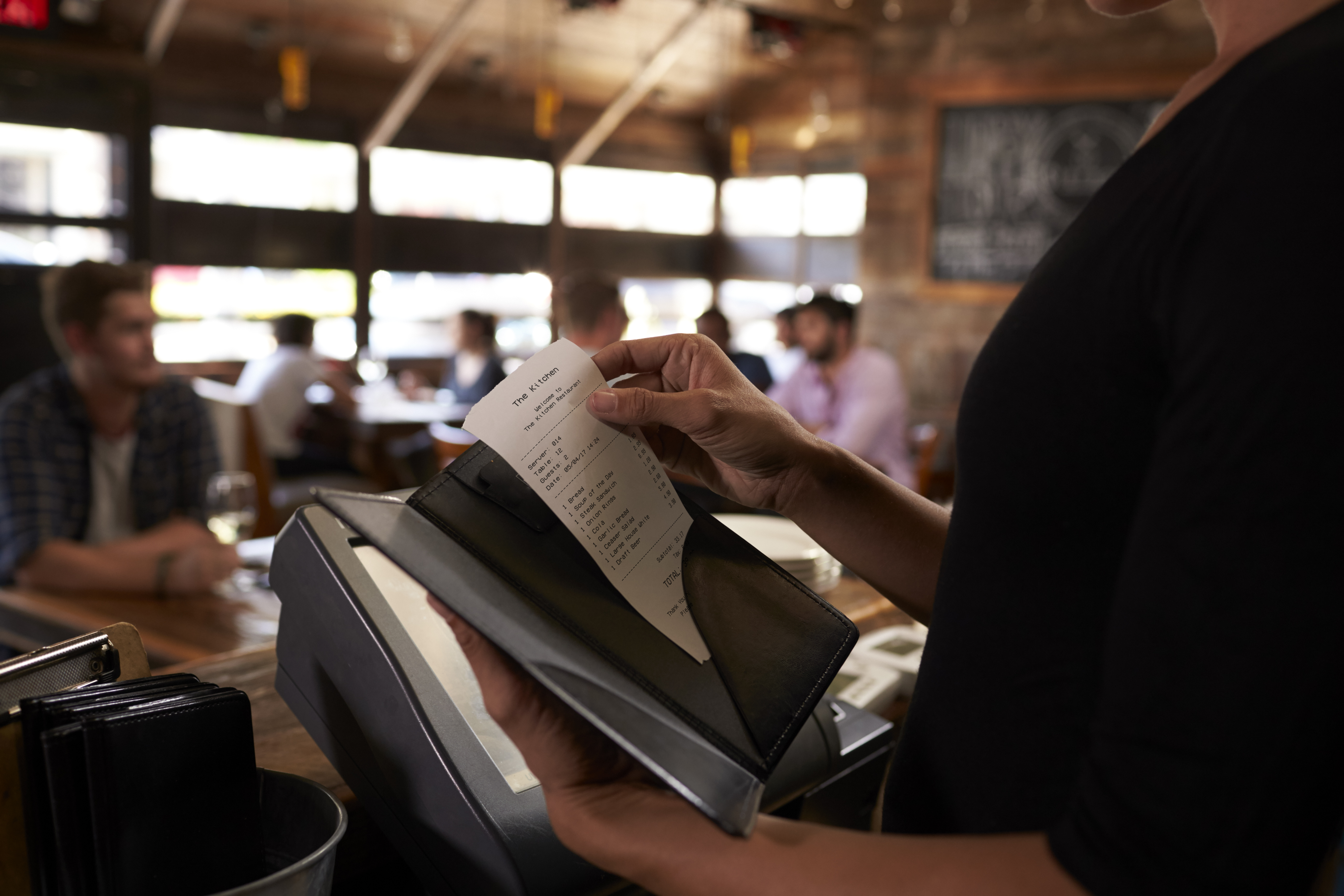 A restaurant worker holding a bill | Source: Shutterstock