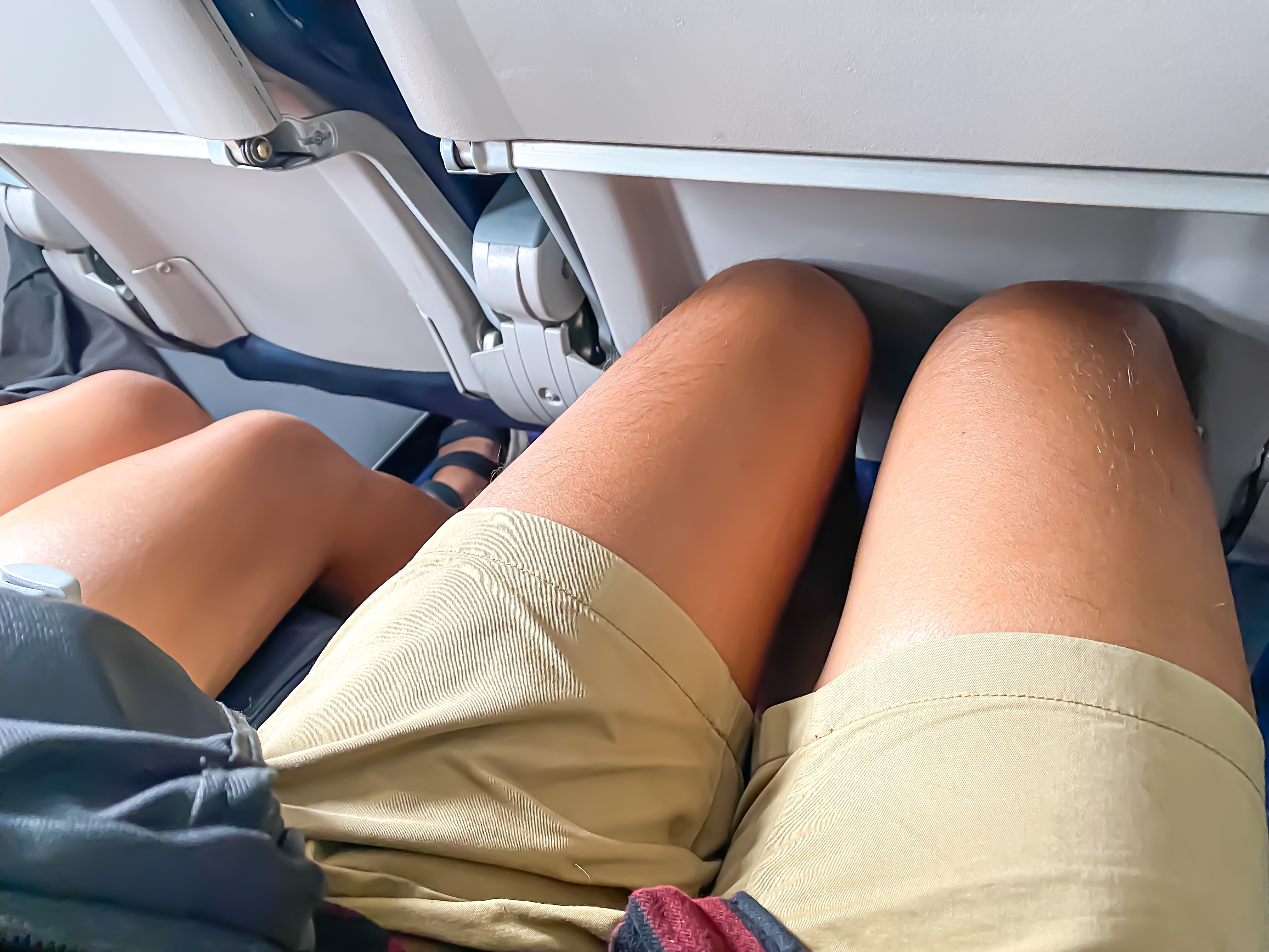 Legs of people sitting together during a flight | Source: Shutterstock