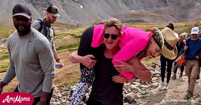 Strong stranger carries a woman down the mountain in his arms
