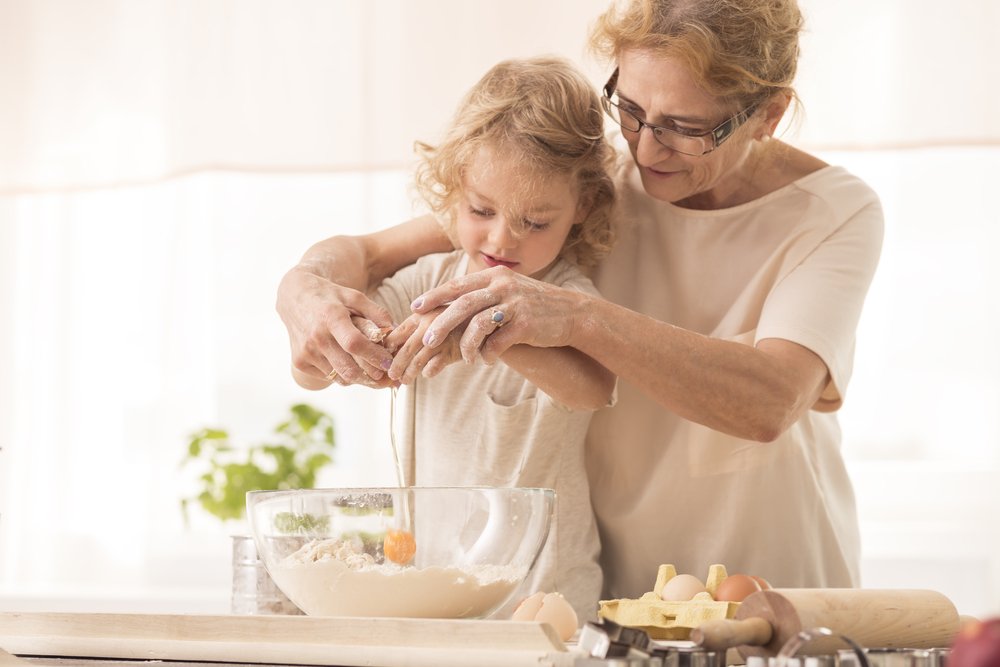 Grandmother helping her granddaughter out in the kitchen | Photo: Shutterstock