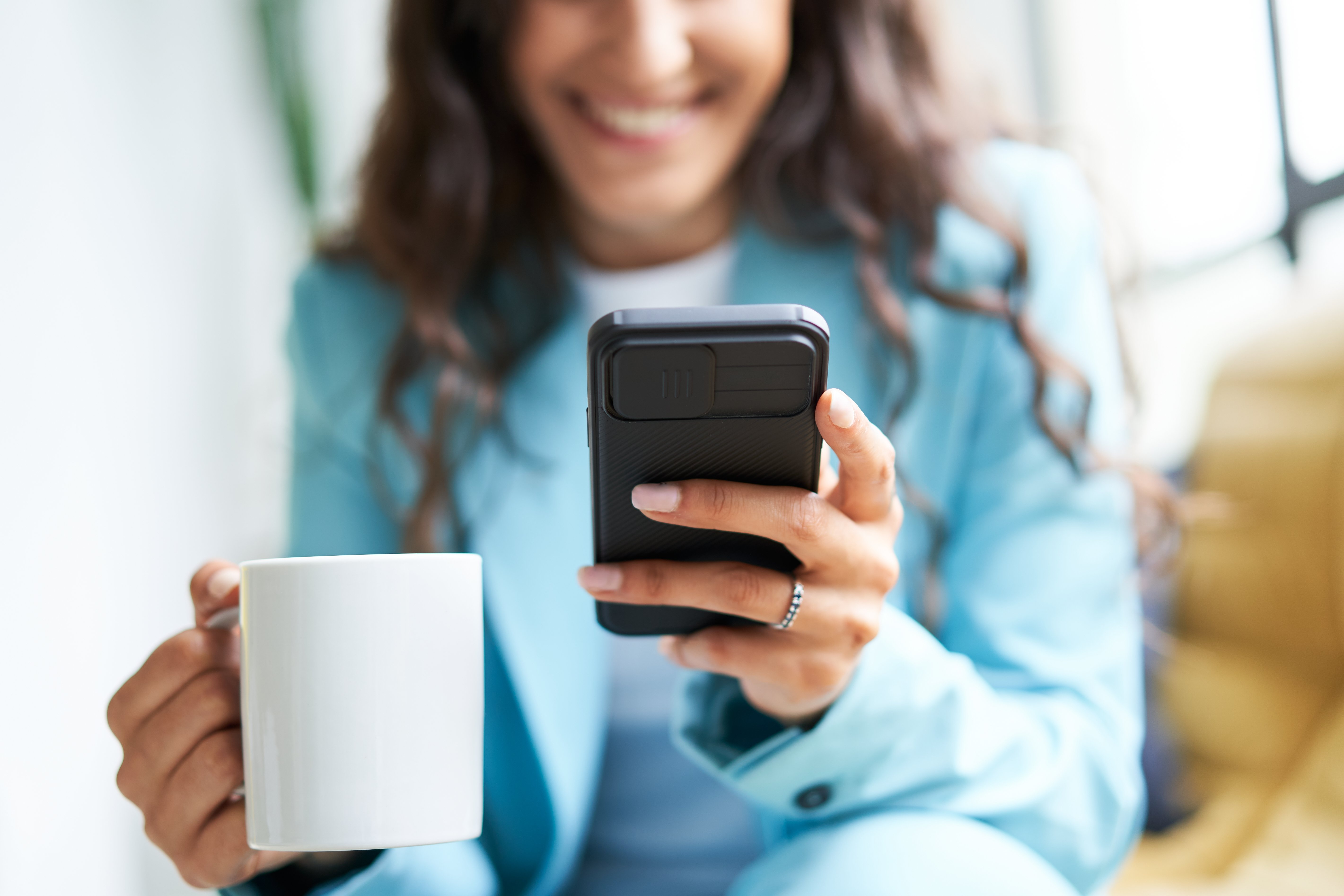 Mujer sonriendo y viendo su teléfono móvil. | Foto: Shutterstock