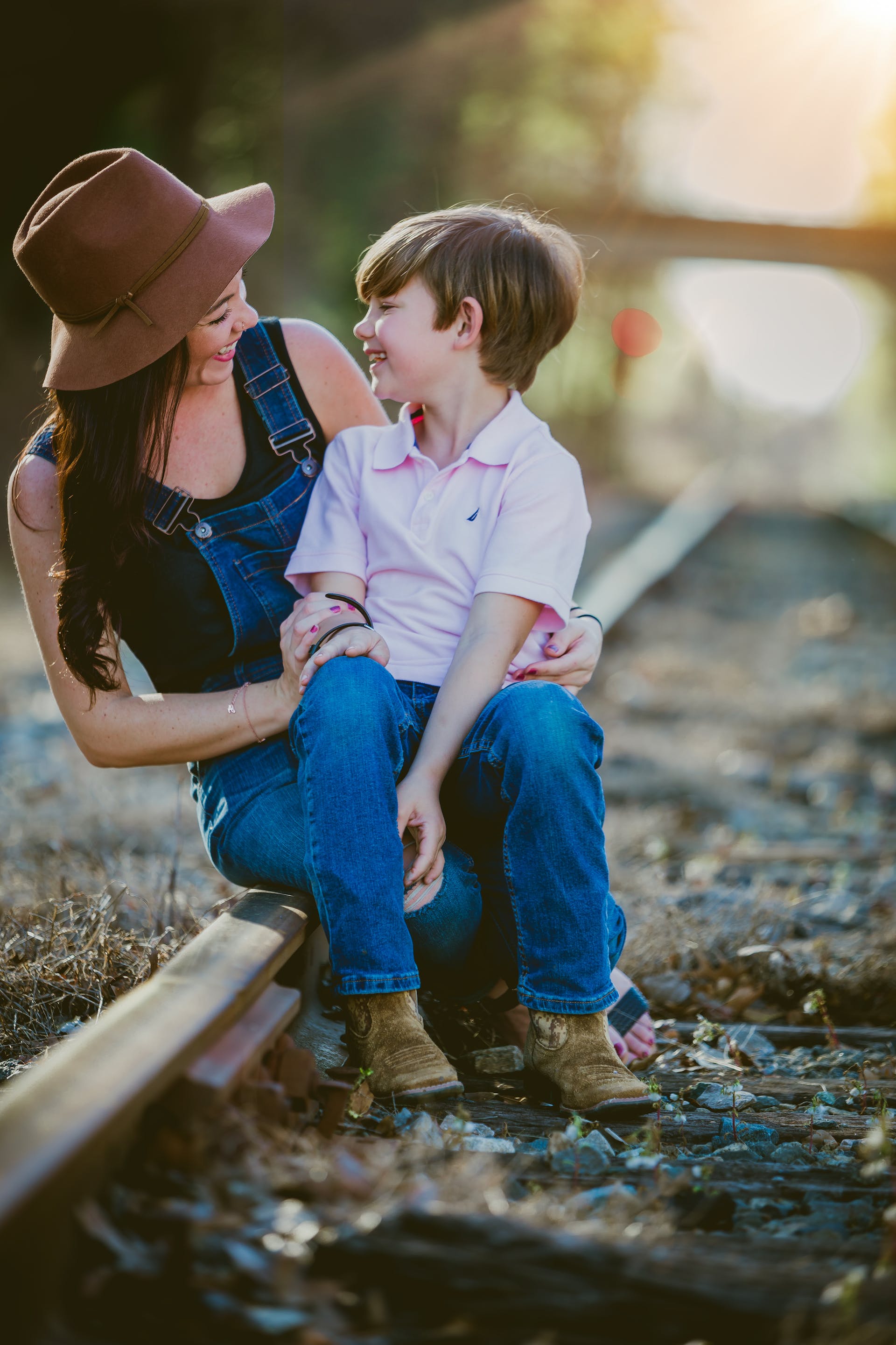 Mother and son sitting on a railway track | Source: Pexels