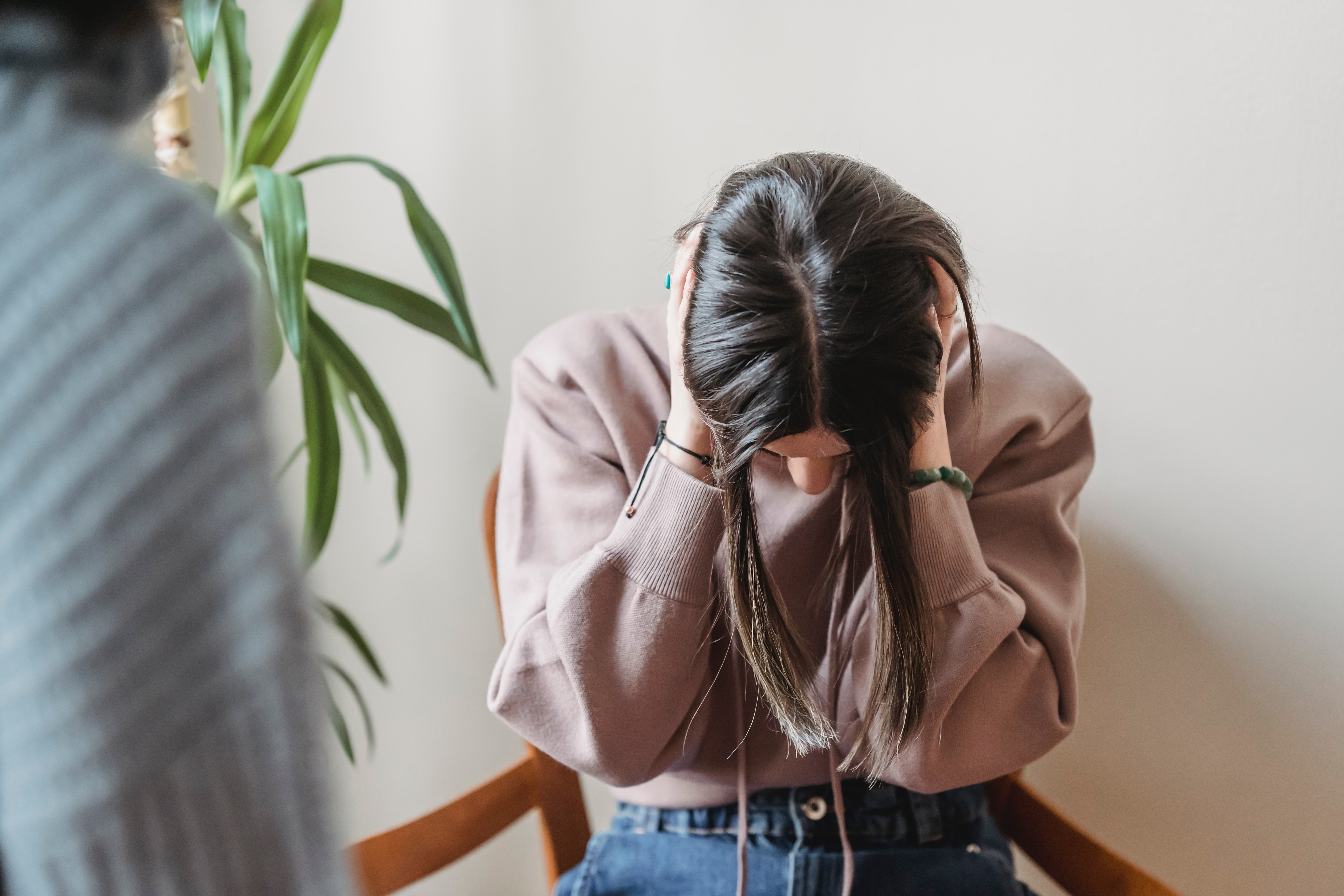 An upset woman looking down, covering her ears with her hands while talking to someone else | Source: Pexels