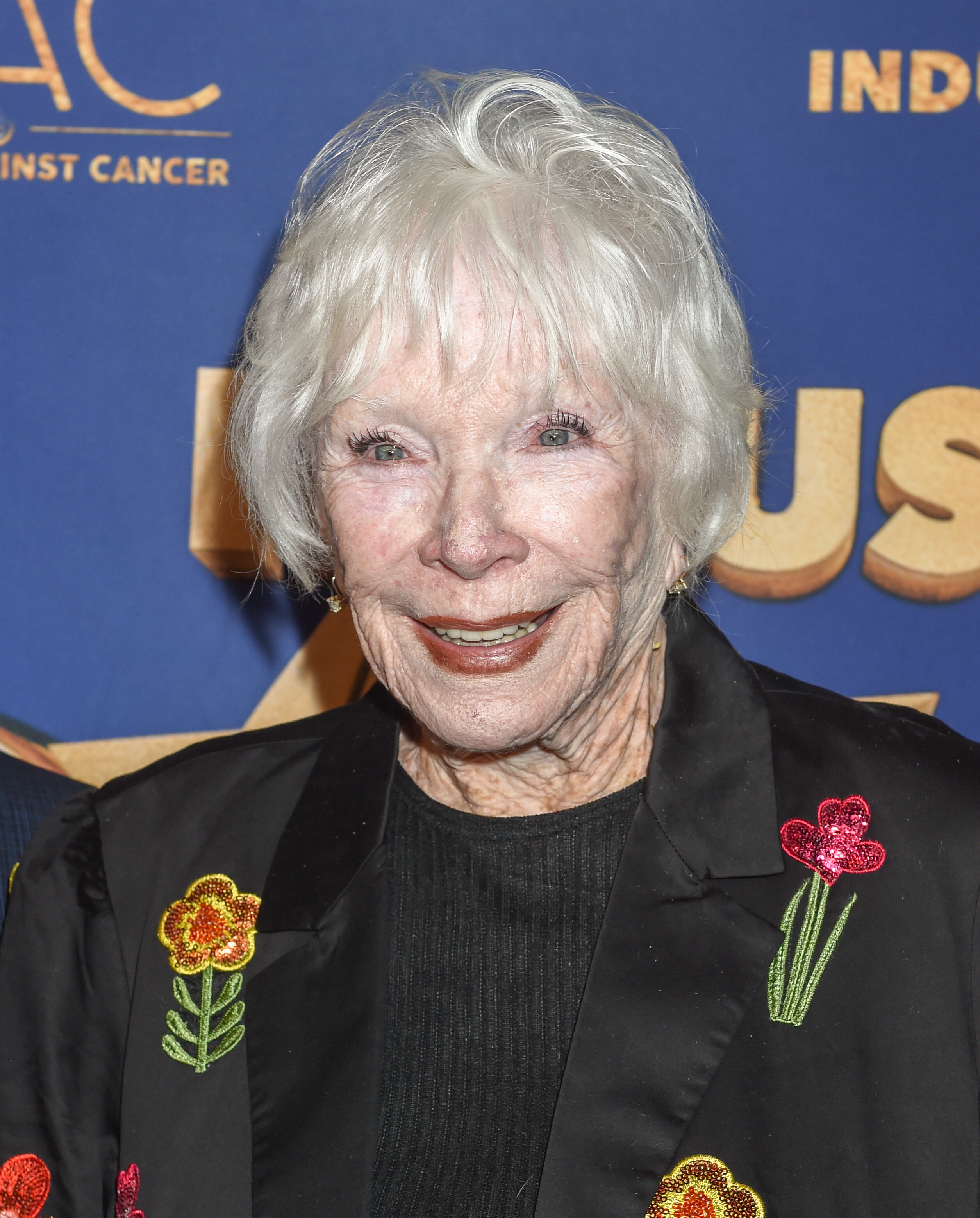 Beaming beneath a black jacket embroidered with colorful florals, MacLaine brings warmth and whimsy to the 2023 Industry Dance Awards. The screen legend's presence is both joyful and iconic as she honors a night dedicated to artistic brilliance.