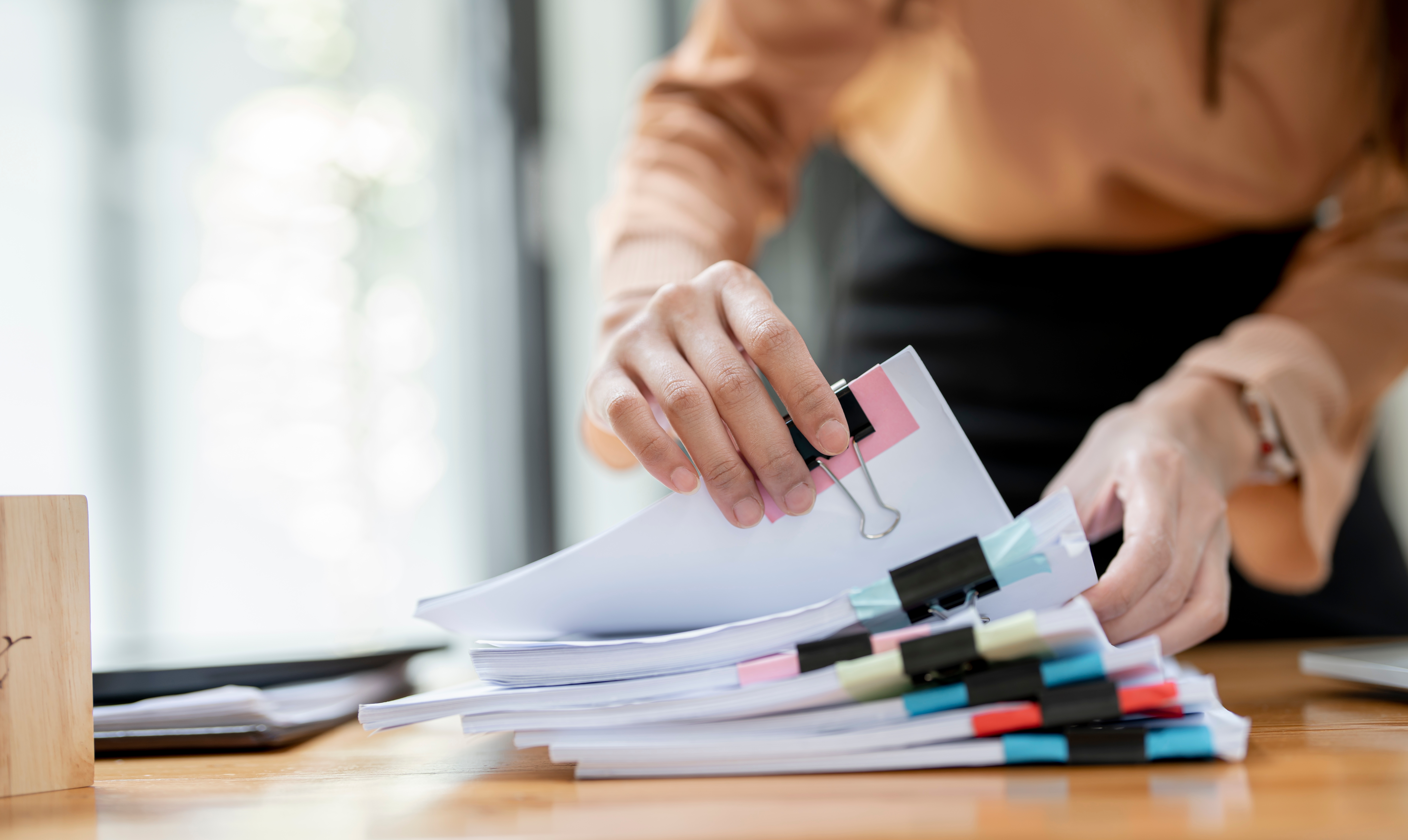 Businesswoman hands working in Stacks of paper files for searching documents | Source: Shutterstock.com