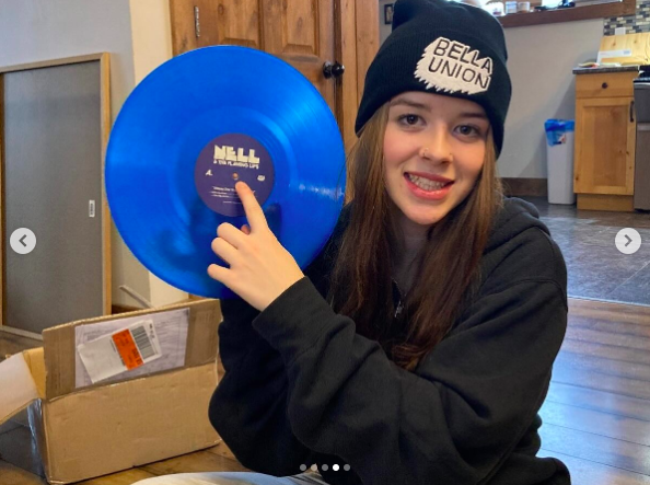 Nell Smith posing for a picture with her blue vinyl, posted on October 7, 2024 | Source: Instagram/mrsimonrayemond