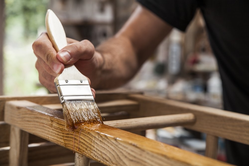 Hombre sosteniendo un pincel oara aplicar pintura de barniz en muebles de madera. | Fuente: shutterstock Hombre sosteniendo un pincel oara aplicar pintura de barniz en muebles de madera. | Fuente: shutterstock