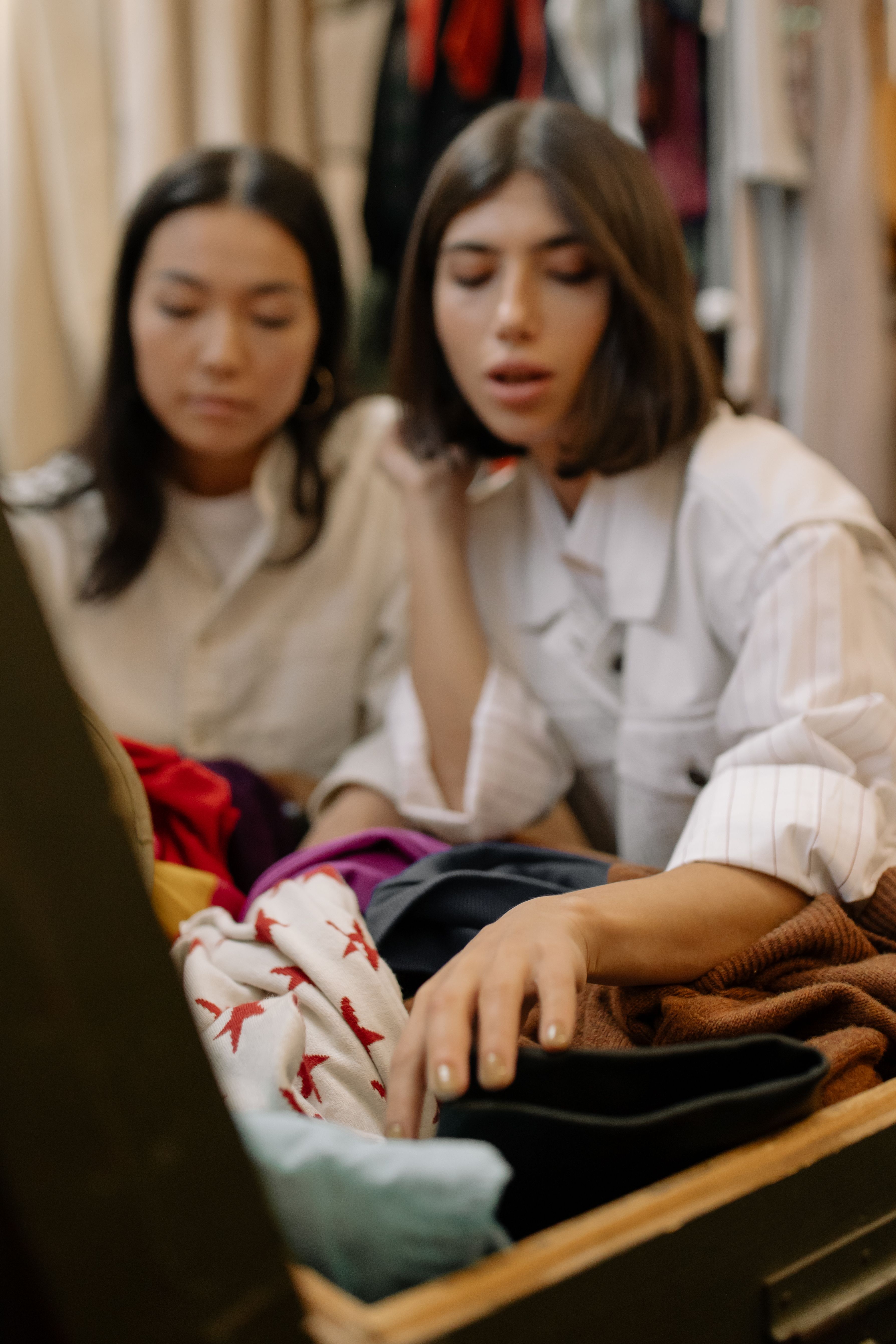 Two women sort through a selection of clothes. | Source: Pexels
