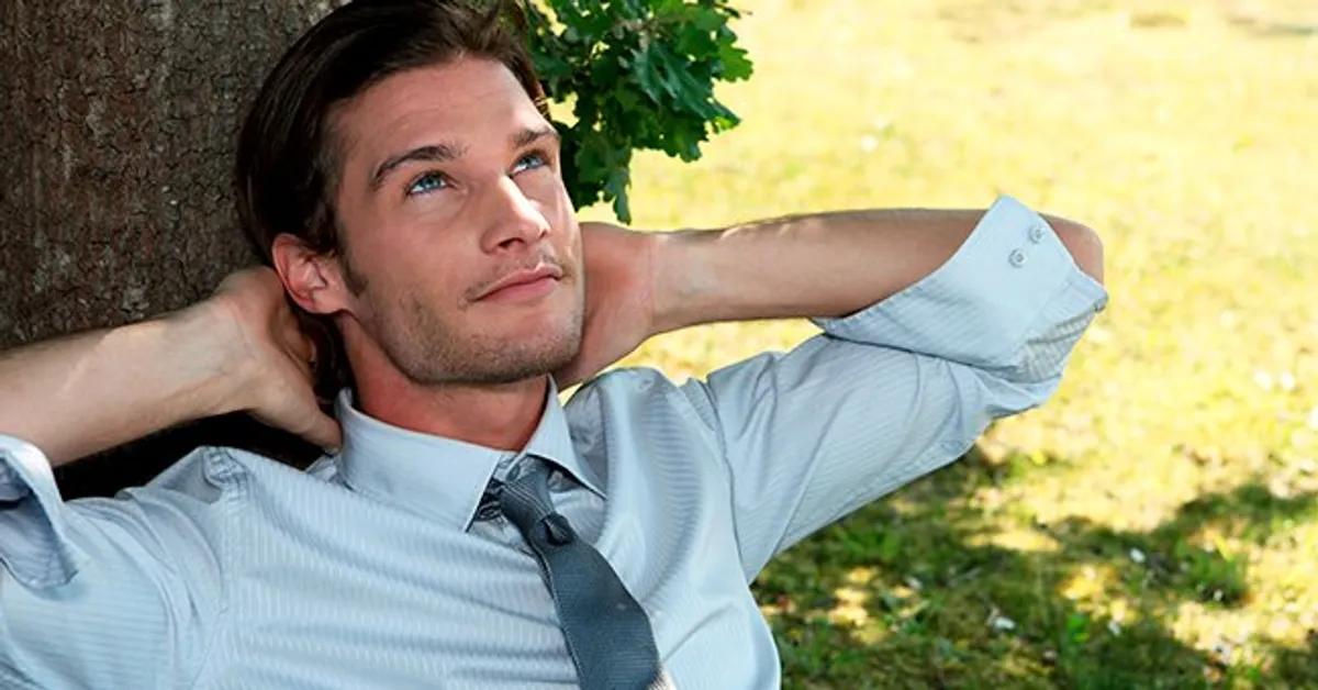 Photo d'un homme se relaxant contre un arbre. | Photo : Shutterstock
