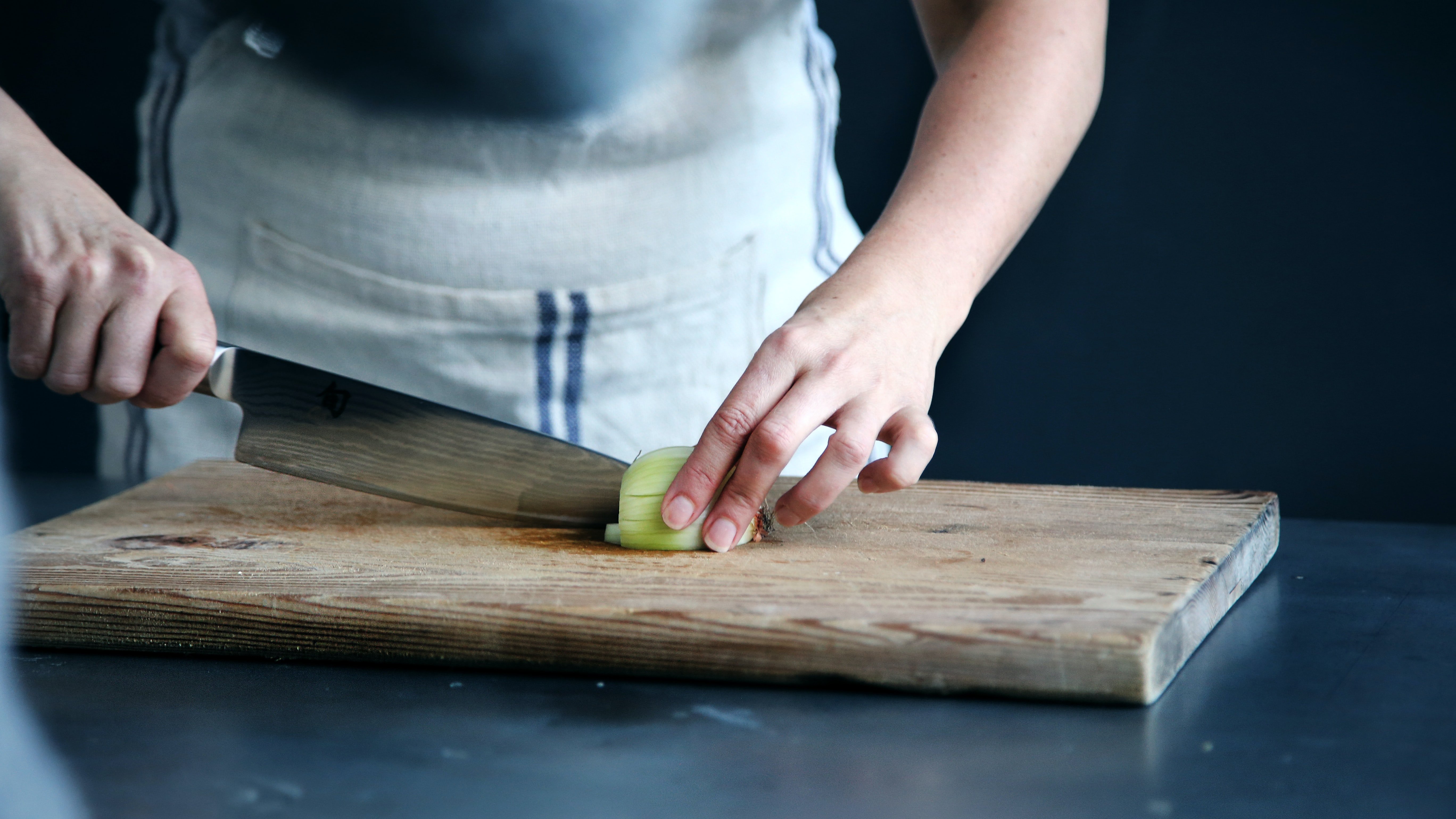 Una persona corta vegetales en una tabla. | Foto: Unsplash