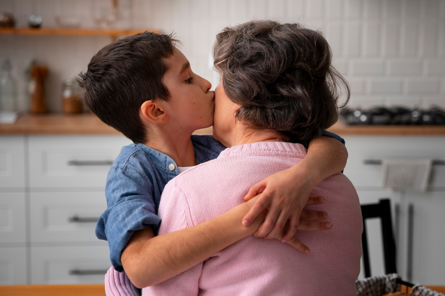 A little boy kissing his grandmother on her cheek | Source: Freepik