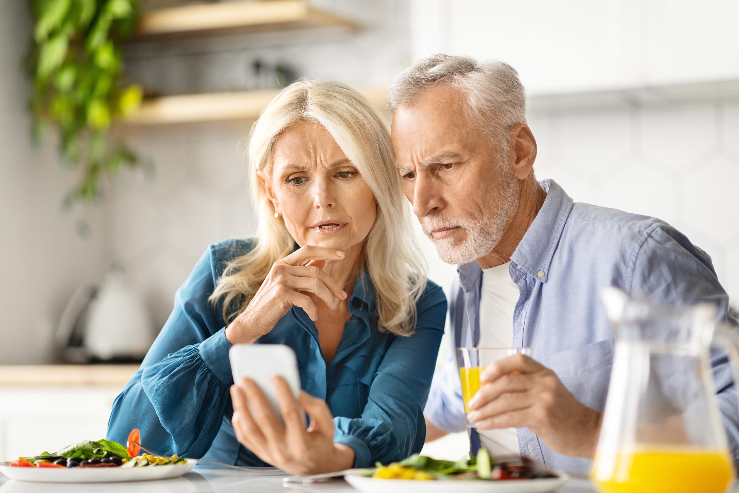 Older couple looking worried while viewing a mobile phone | Source: Shutterstock