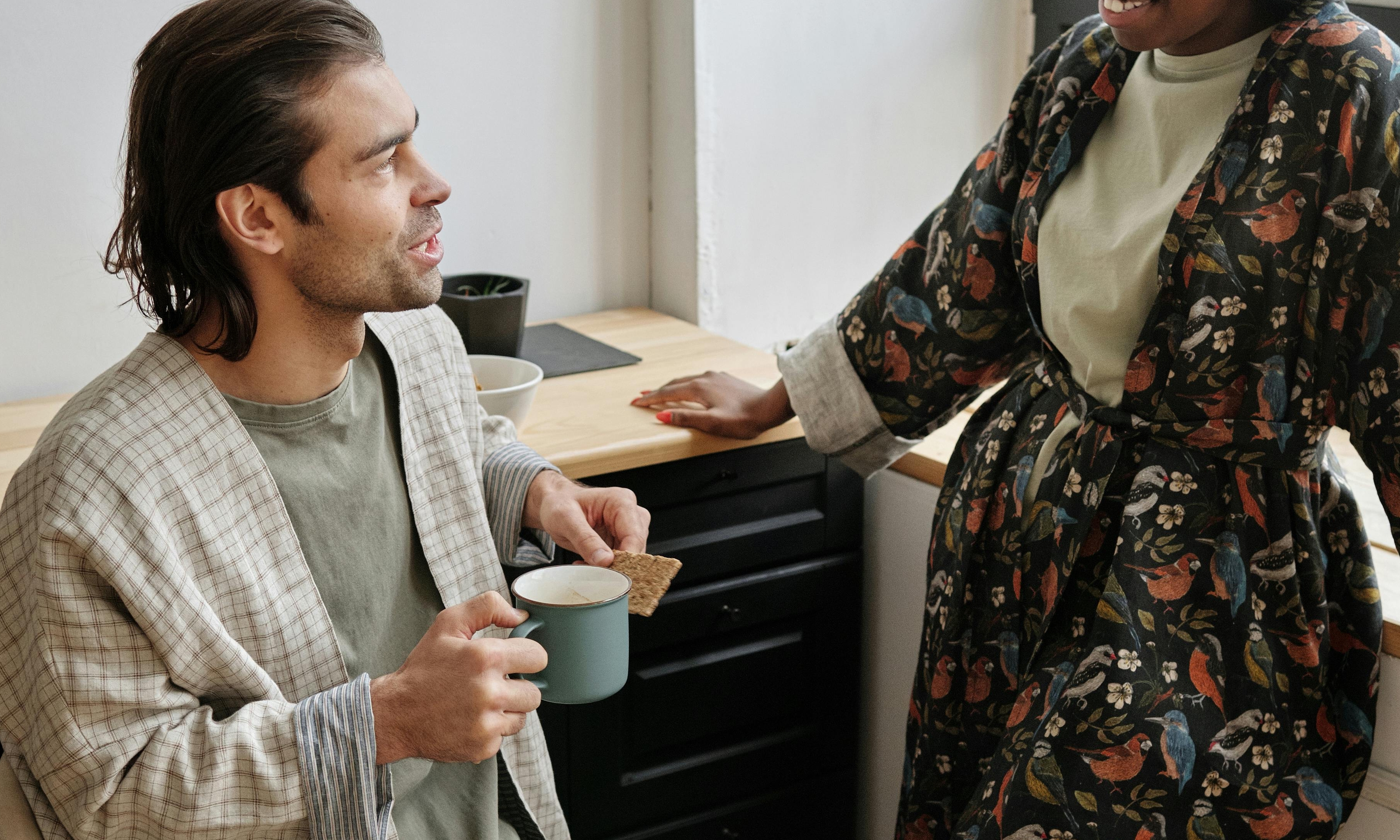 In the kitchen, a woman forces a smile as her husband chats | Source: Pexels