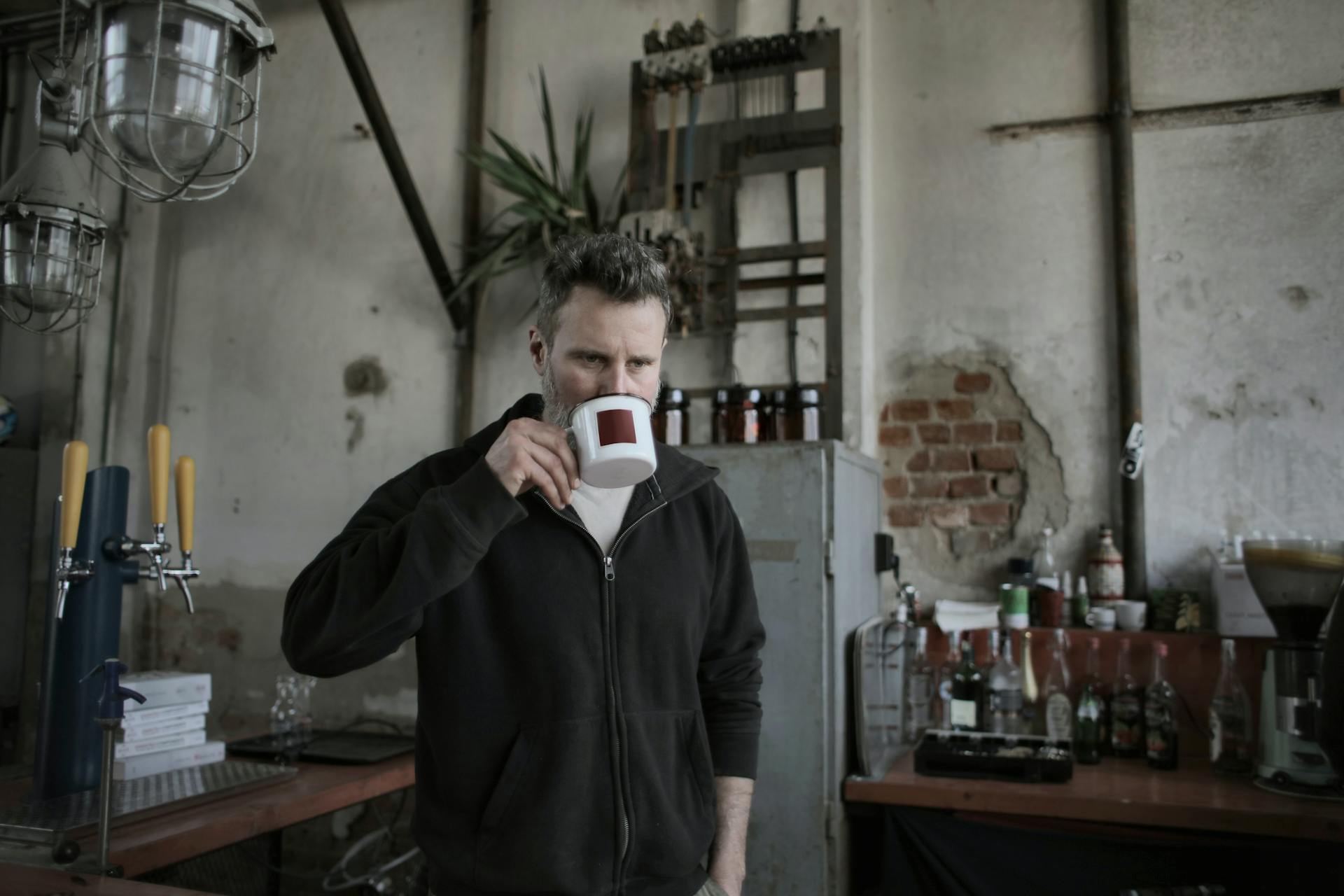 A man drinking from a cup in the kitchen | Source: Pexels