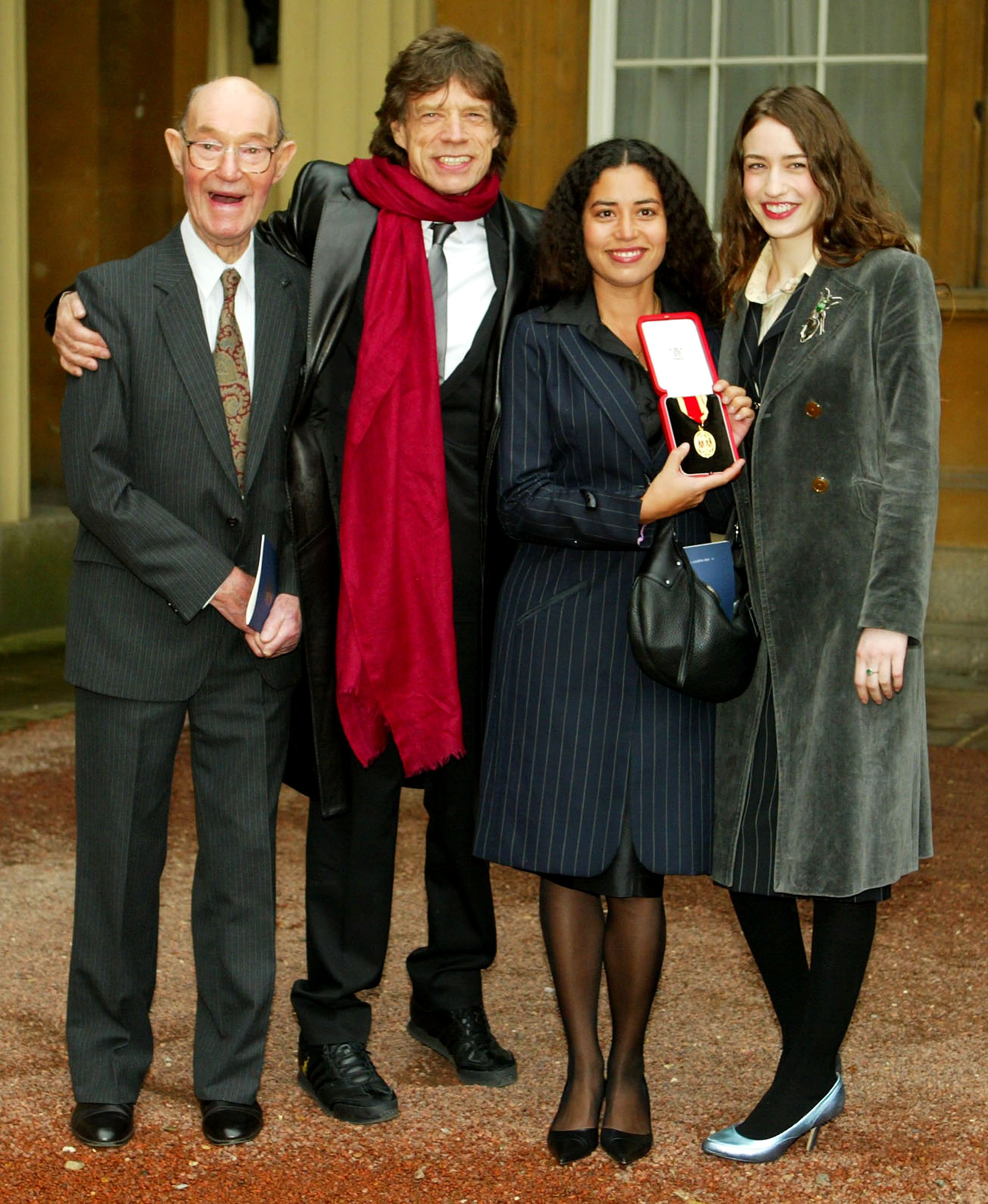 Father Joe with veteran rocker Mick Jagger and daughters Karis and Elizabeth at Buckingham Palace on December 12, 2003 in London. | Source: Getty Images