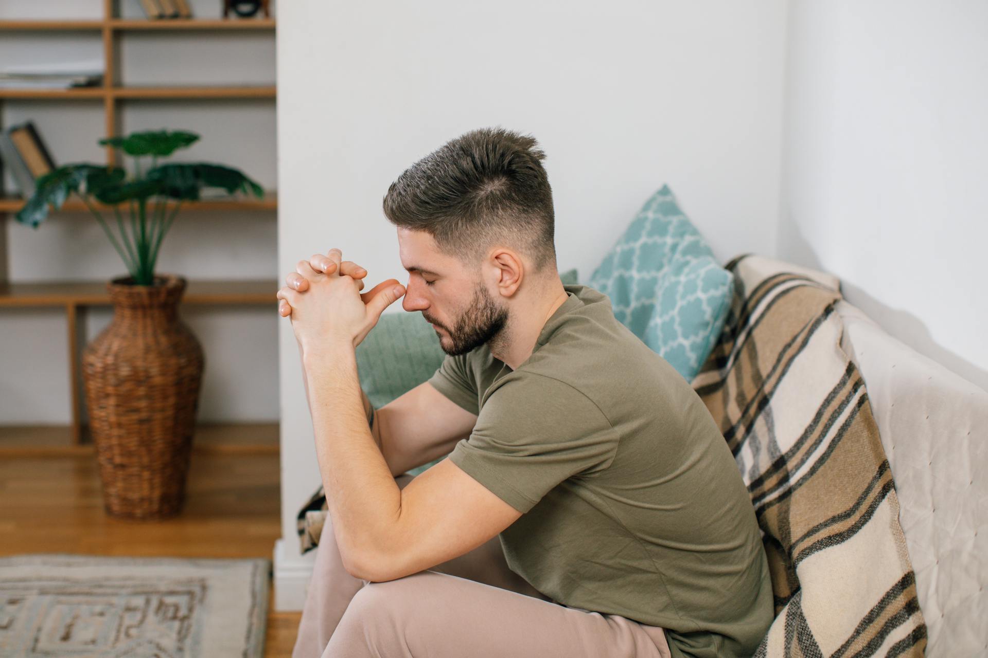 A man sitting on the couch with his hands clasped tight | Source: Pexels