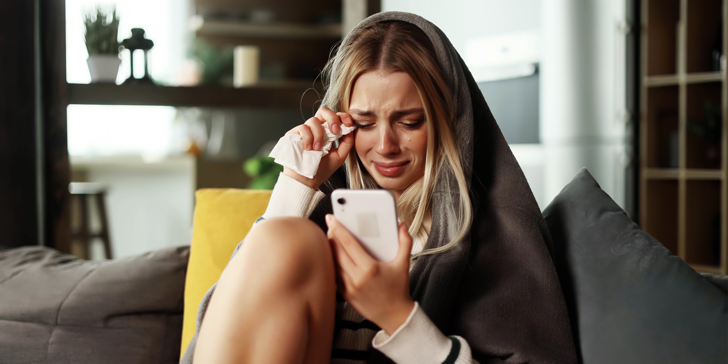 A teary-eyed woman holding a phone | Source: Shutterstock