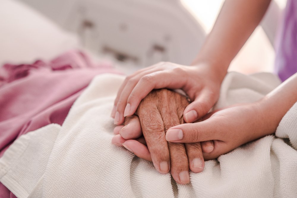 Joven sosteniendo la mano de su abuelo en cama. │Foto: Shutterstock