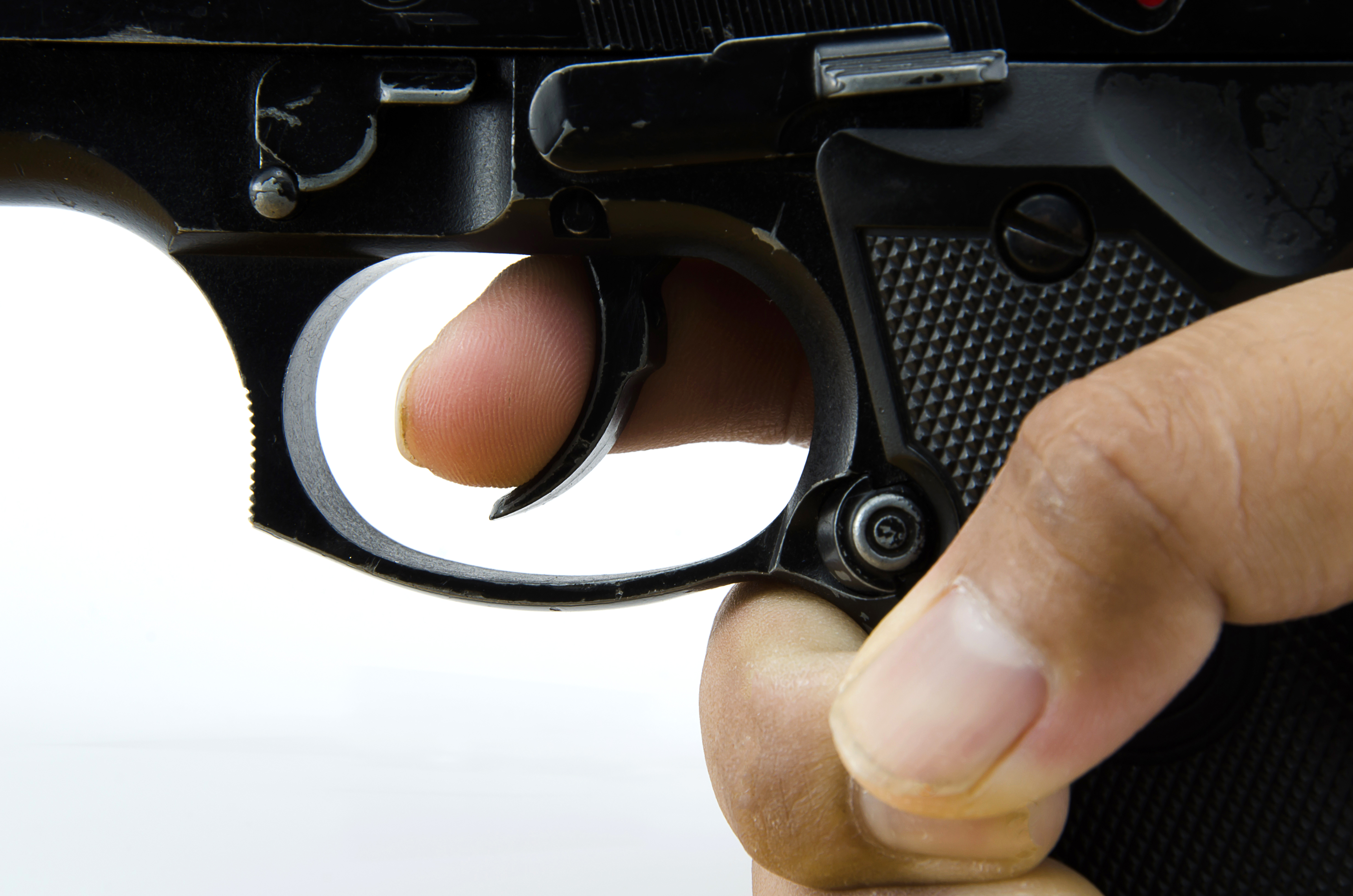 Closes up the finger on the trigger of the gun. | Source: Shutterstock