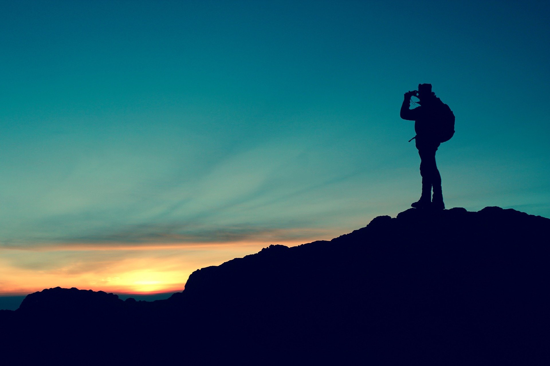 A silhouette of a hiker taking in the views atop a mountain | Photo: Pixabay