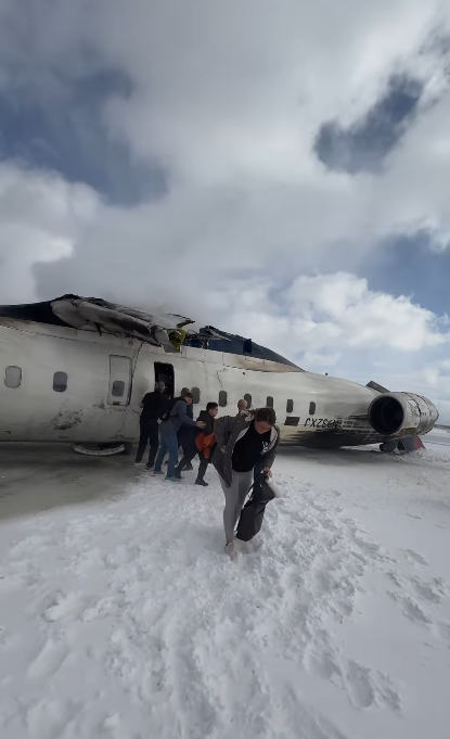 Smoke bursts from the plane as passengers climb out and move away across the snow-covered ground, posted on February 18, 2025. | Source: Instagram.com/eggxit