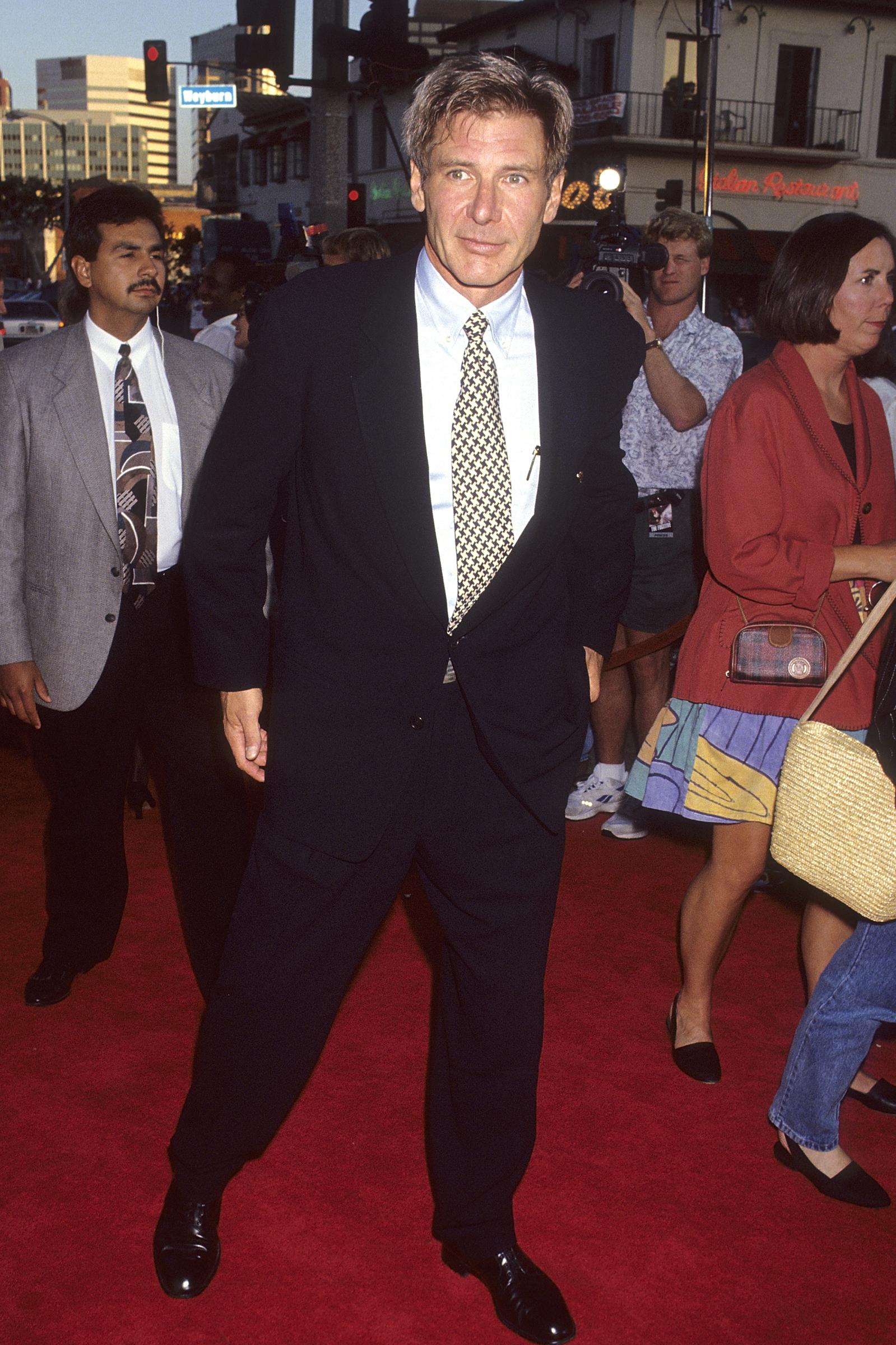 Dressed for the Westwood premiere of his hit film, "The Fugitive," Ford stands on the red carpet. The actor's broad-shouldered stance showcases the athletic physique he has maintained throughout his decades-long career. | Source: Getty Images