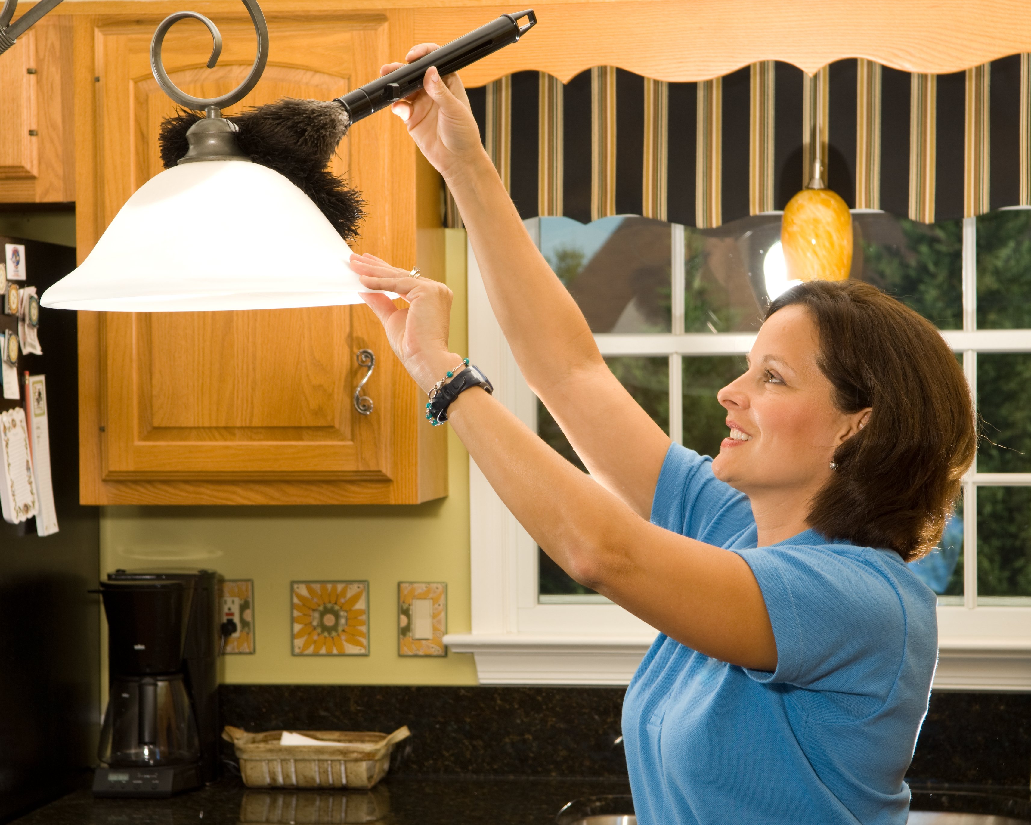 Eine Frau, die Küchenlampe abstaubt | Quelle: Getty Images