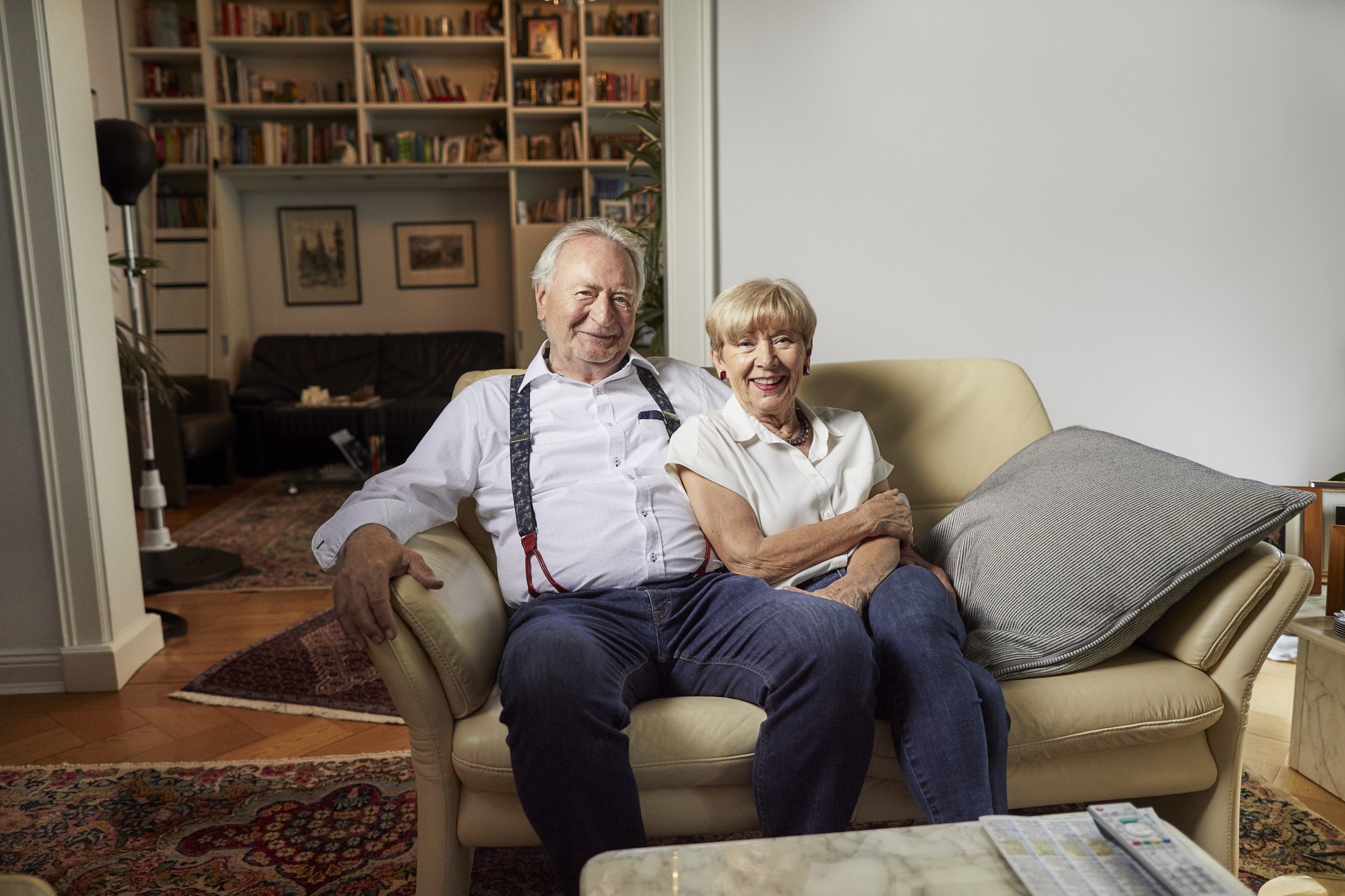Un couple souriants assis sur un canapé à la maison. | Photo : Getty Images