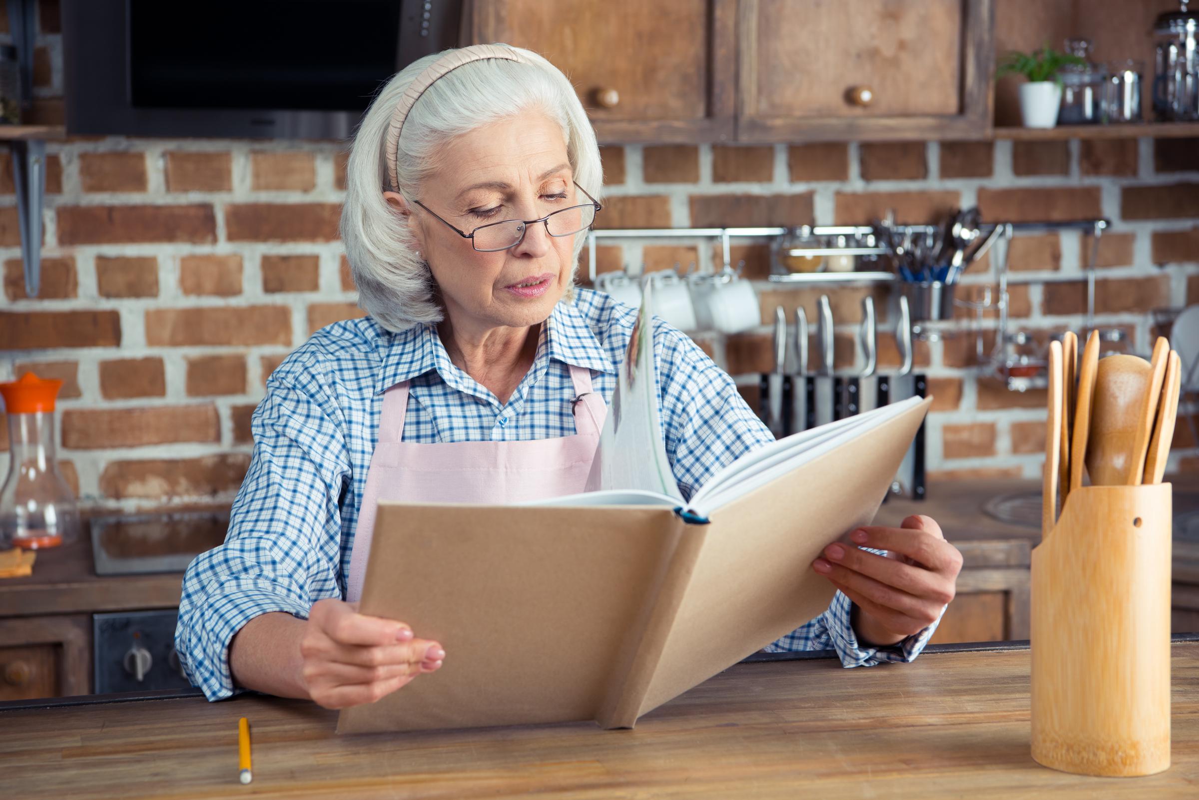 A woman reading a cookbook in the kitchen | Source: Shutterstock