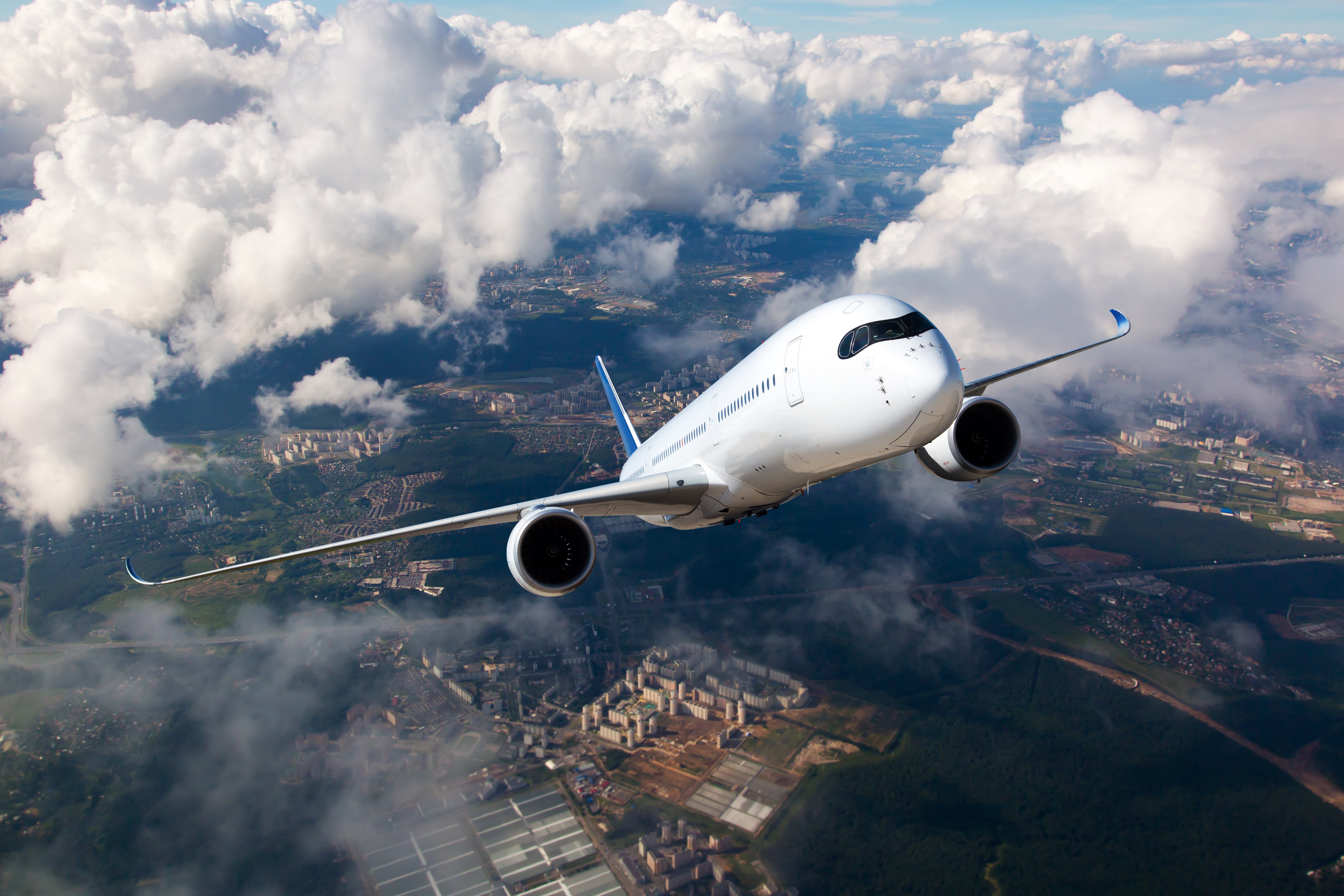 Weißes Passagierflugzeug steigt durch die Wolken | Quelle: Shutterstock