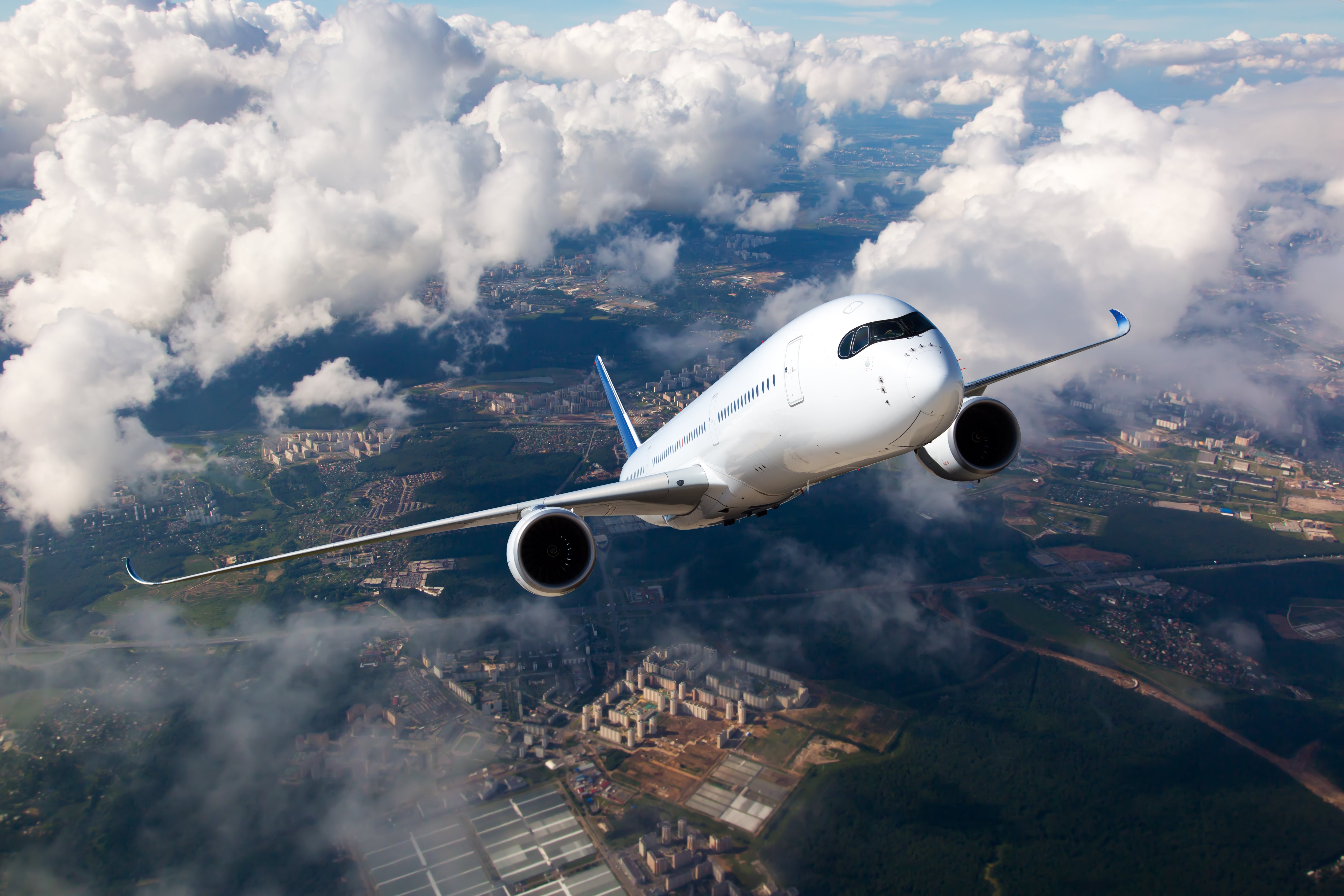 Weißes Passagierflugzeug steigt durch die Wolken | Quelle: Shutterstock Weißes Passagierflugzeug steigt durch die Wolken | Quelle: Shutterstock